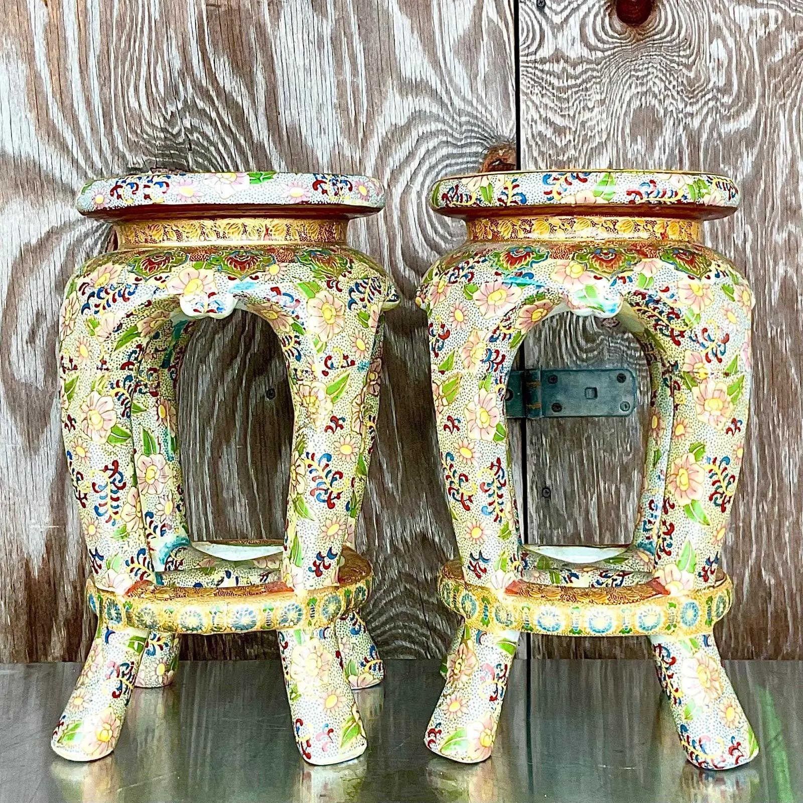 Fabulous pair of vintage Ceramic low stools. Beautiful floral design in bright clear colors. Tipped in gold for a little extra shine. Perfect as additional seating indoors or outside. Acquired from a Palm Beach estate.