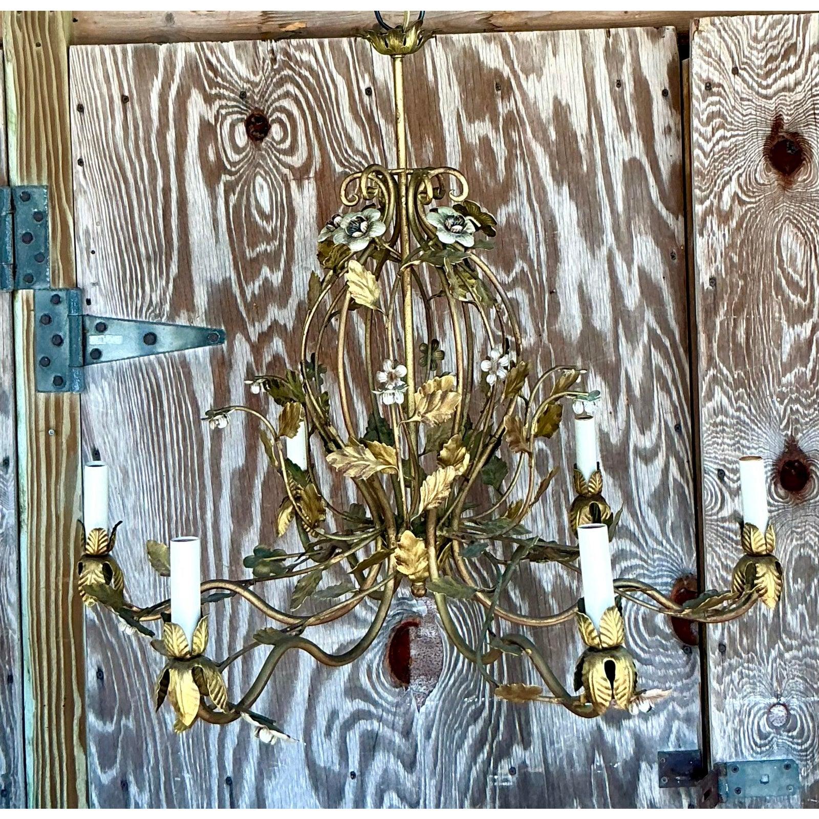 Illuminate your home with the timeless elegance of this vintage Regency-style gilt floral chandelier. Exquisitely crafted from metal with a rich gilt finish, this captivating fixture features gracefully scrolling arms adorned with delicate,