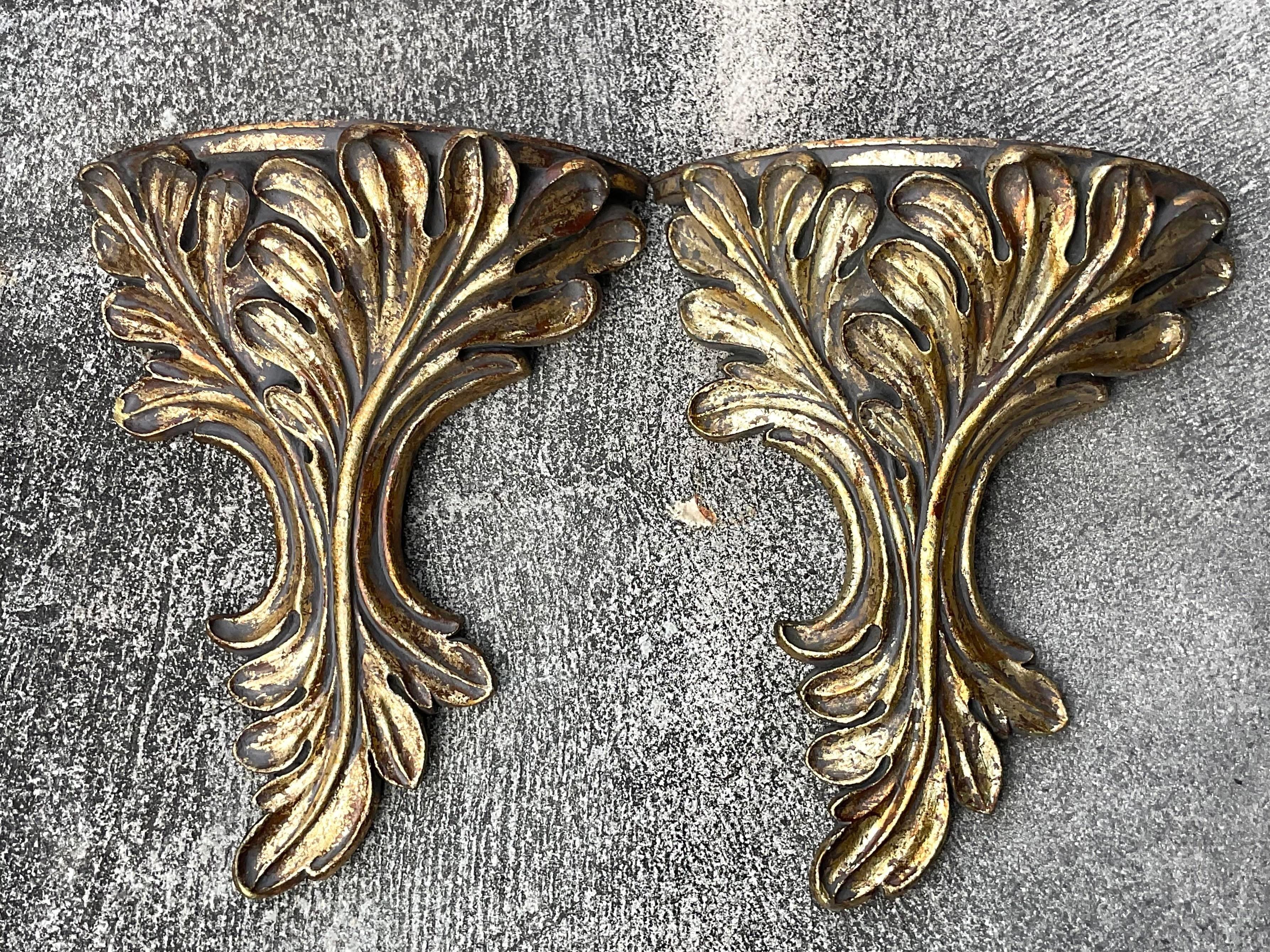 A fabulous pair of vintage Regency wall brackets. Chic hand carved laurels with a silvery gold finish. Acquired from a Palm Beach estate.