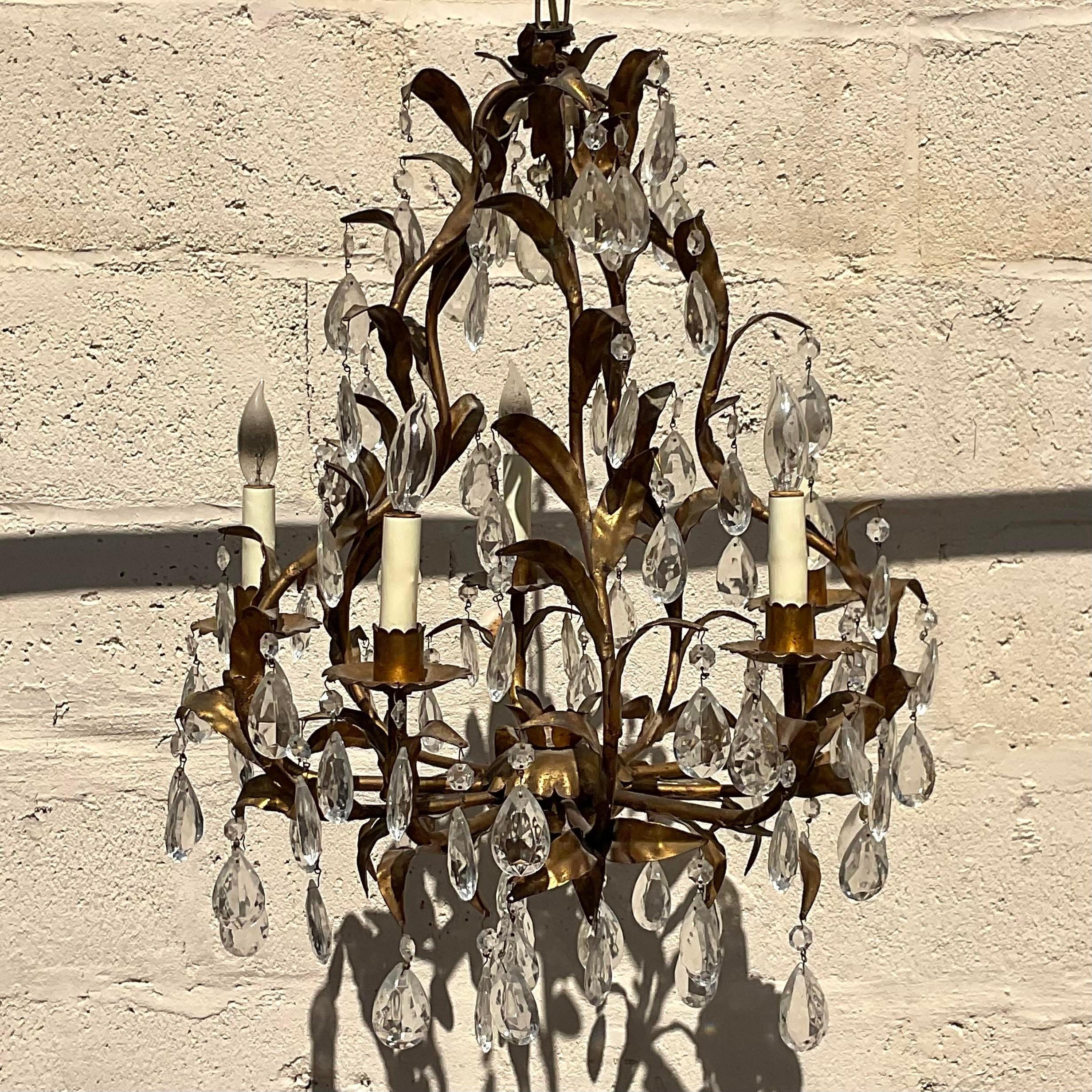 A fabulous vintage Regency chandelier. Beautiful leaf design with a gilt leaf finish and drop crystals. Acquired from a Palm Beach estate.