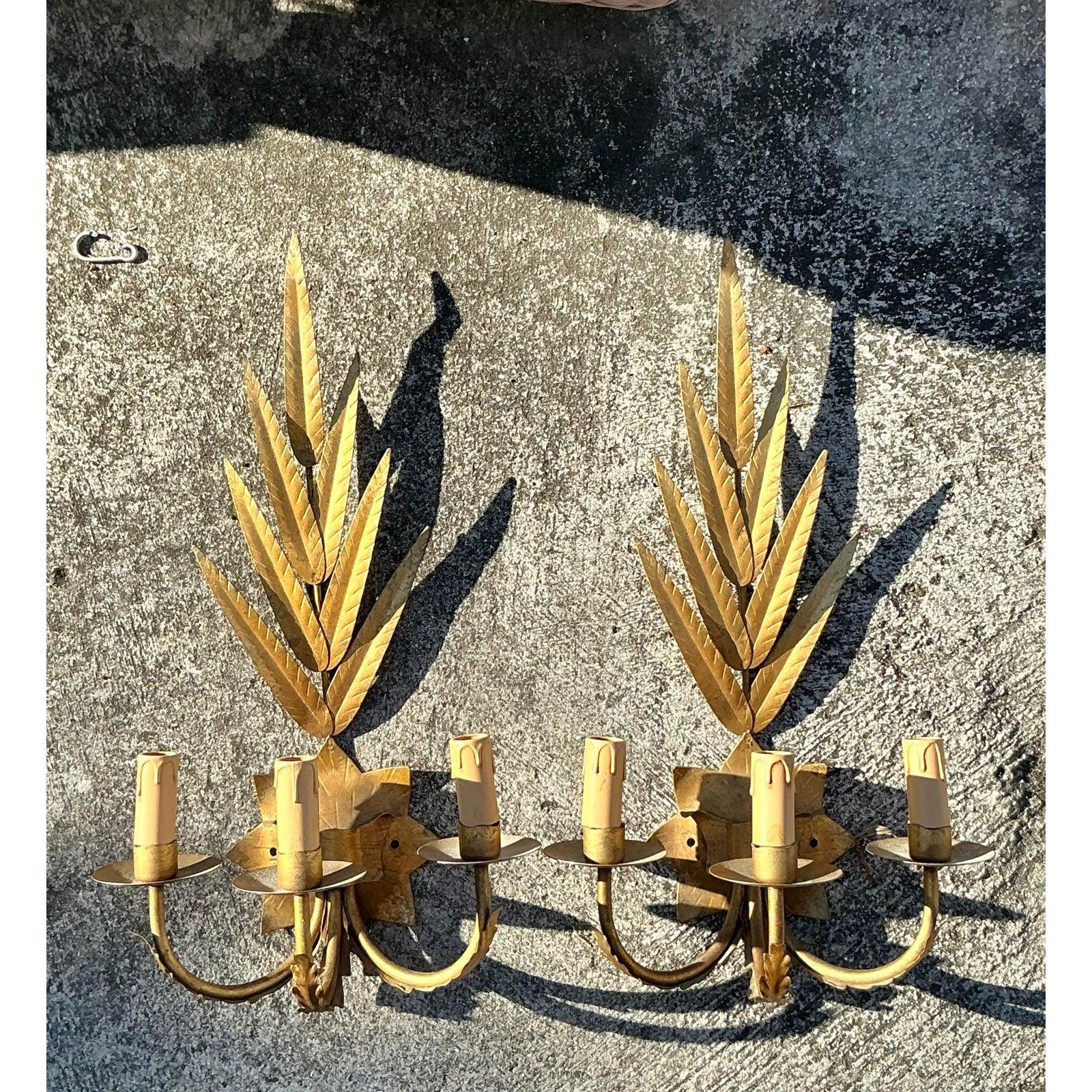 Haz una declaración audaz con este exquisito par de apliques vintage de estilo Regencia con hojas doradas. Con un elegante follaje de metal dorado y brazos dobles estilo vela, estos apliques destilan el glamour clásico de la Regencia de Hollywood.