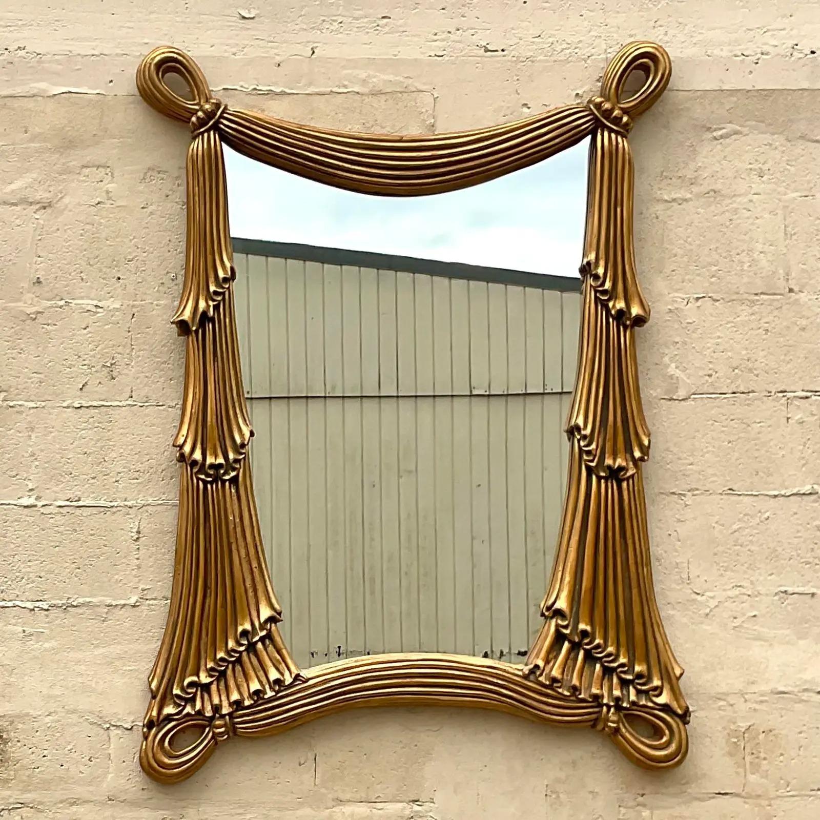 A fantastic vintage Regency wall mirror. A chic swag design in a bright gilt finish. Acquired from a Palm Beach estate.