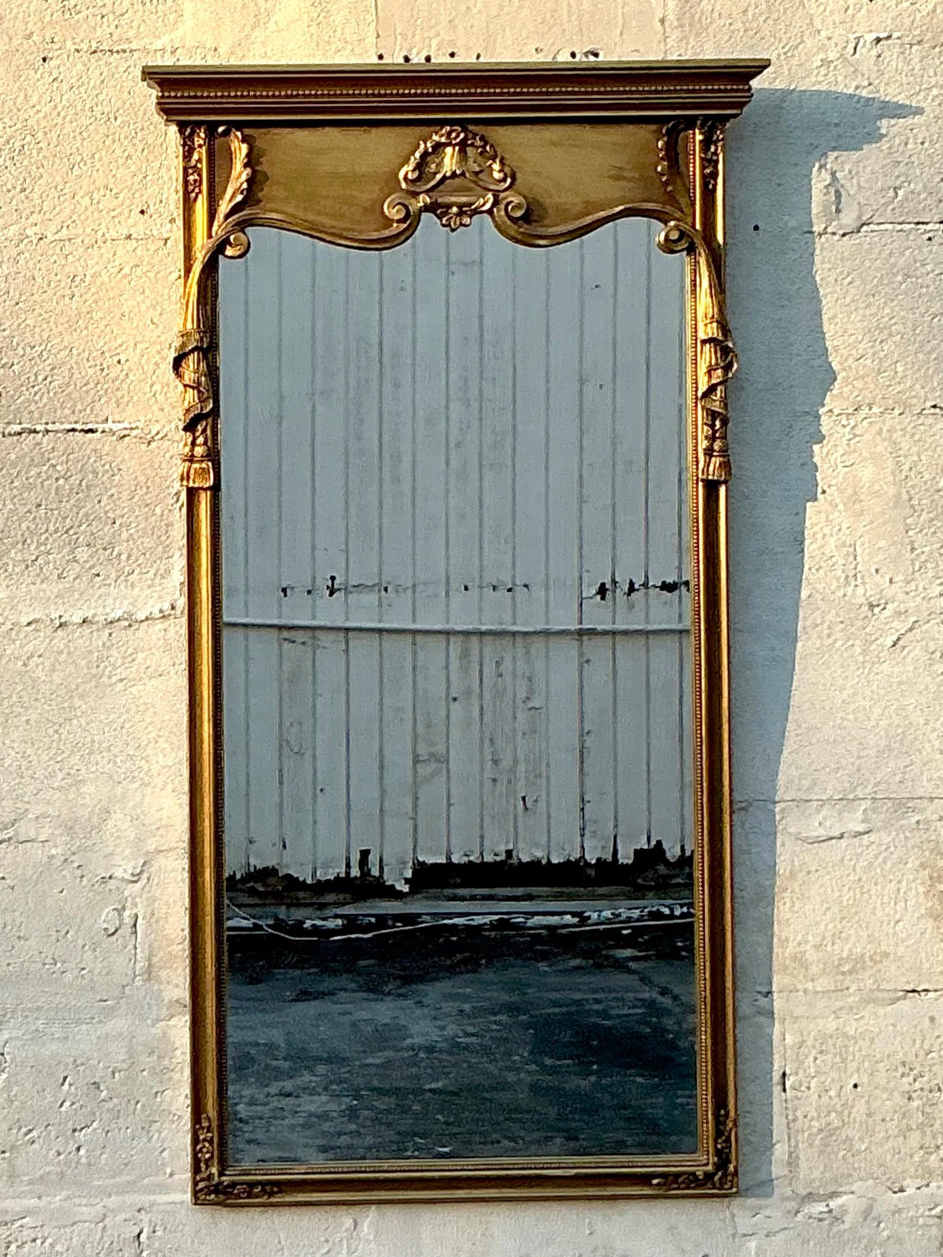 Un superbe miroir doré Vintage By avec un motif de guirlandes ornementales. Le cadre aux détails complexes présente des ornements dorés, notamment des guirlandes drapées, des accents floraux et des motifs classiques, incarnant l'élégance