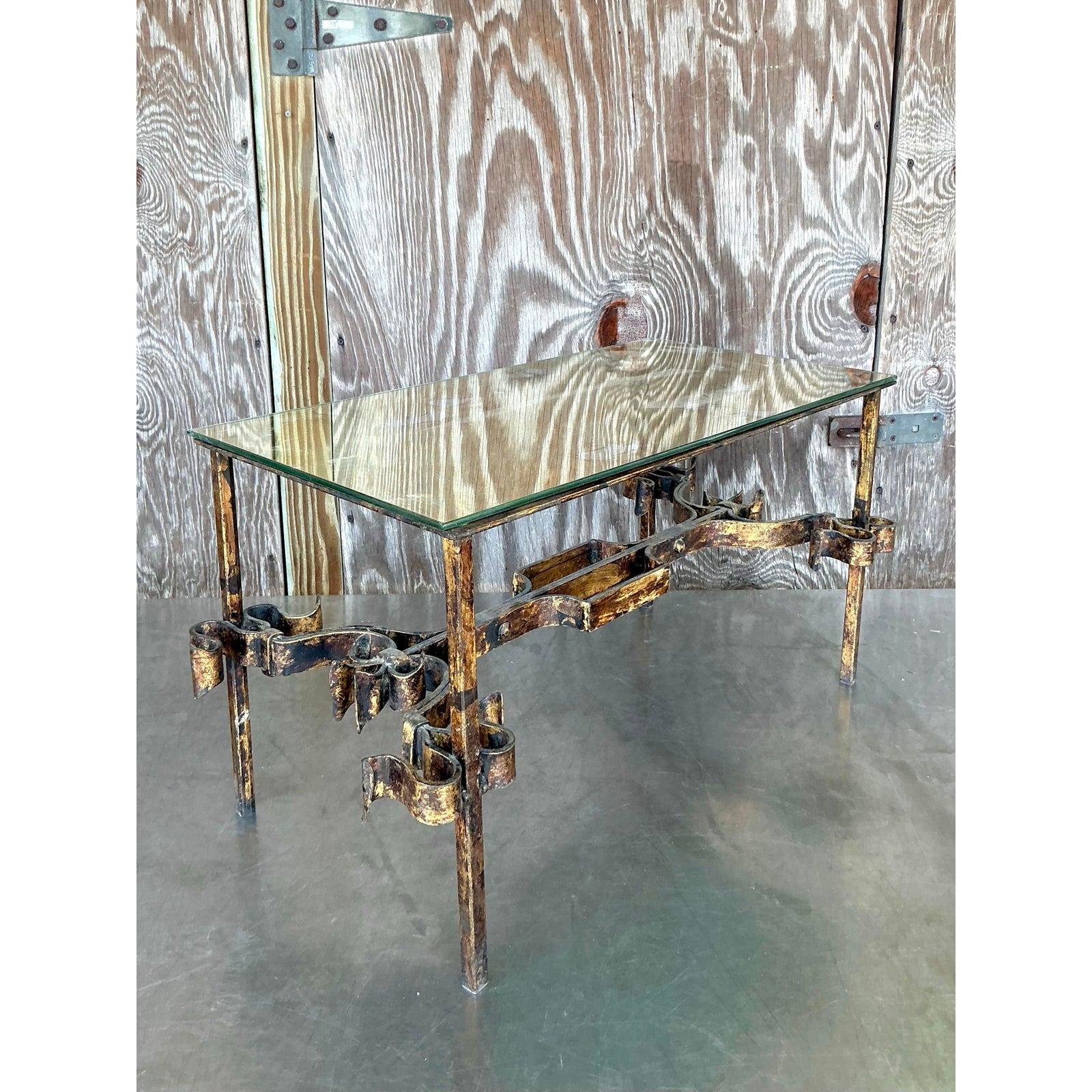 Bring a touch of Hollywood Regency glamour to your living space with this stunning vintage coffee table. The wrought iron base, with its elegant curves and gilt-tipped accents, exudes a sense of sophisticated drama. Its unique design, reminiscent of