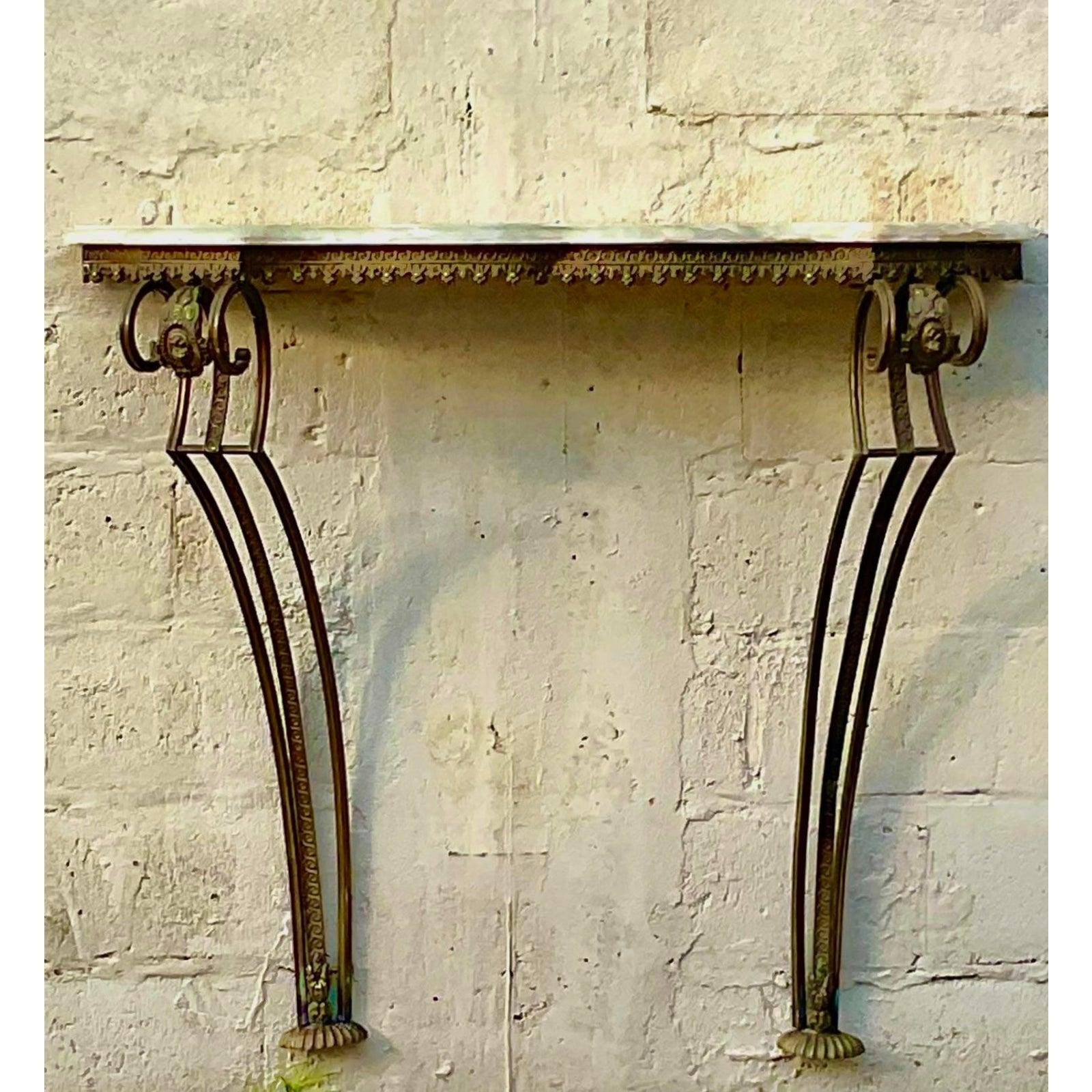 Infunde a tu espacio una dosis de elegancia europea atemporal con esta impresionante consola vintage de pared. La pieza presenta una lujosa encimera de mármol que descansa sobre una base de metal dorado exquisitamente elaborada, que ha desarrollado