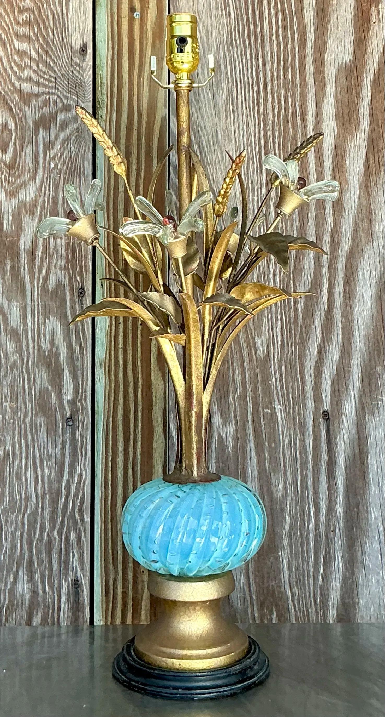 This Vintage Regency Glass Floral Lamp After Murano is a stunning example of timeless elegance and artistry. The lamp features a beautifully crafted glass base adorned with intricate floral details that evoke the exquisite craftsmanship of Murano