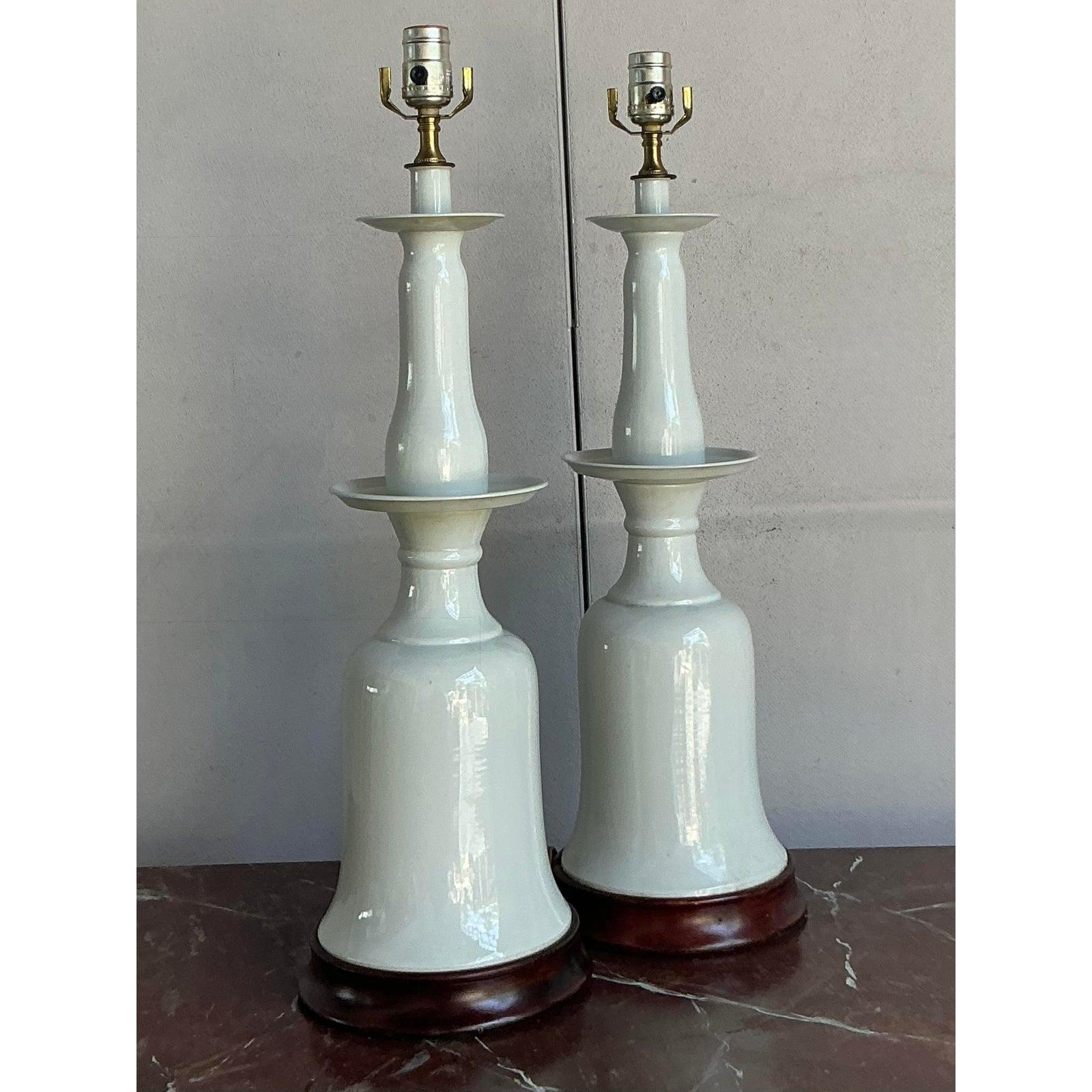 Make a sophisticated statement with this stunning pair of vintage table lamps. Showcasing a striking, stacked silhouette, each lamp is crafted from high-gloss white glazed ceramic, featuring a graceful bell-shaped body and elegant candlestick-style