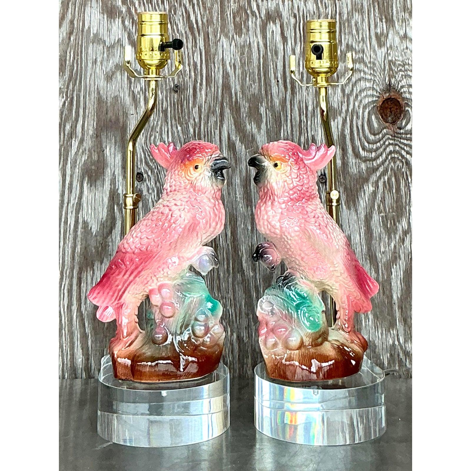 Ajoutez une touche de charme vintage à votre espace avec cette exquise paire de lampes cacatoès en céramique émaillée de style Regency. Les cacatoès roses et corail aux détails complexes, perchés sur des bases sculpturales aux accents verts et