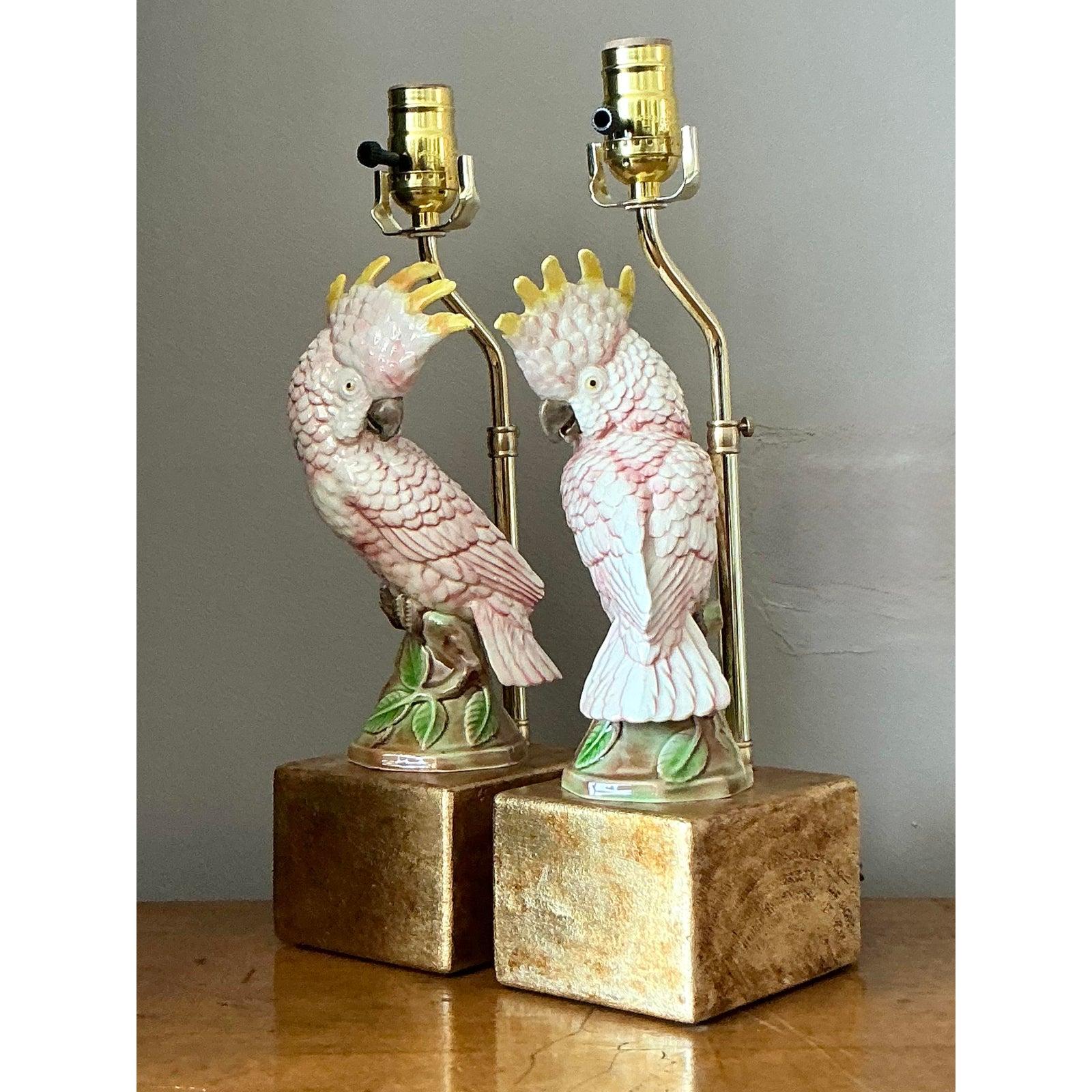 Illuminate your space with the exotic charm and playful glamour of this delightful pair of vintage cockatoo lamps. Each lamp features a beautifully detailed ceramic cockatoo, rendered with soft pink and white plumage and a vibrant yellow crest. The