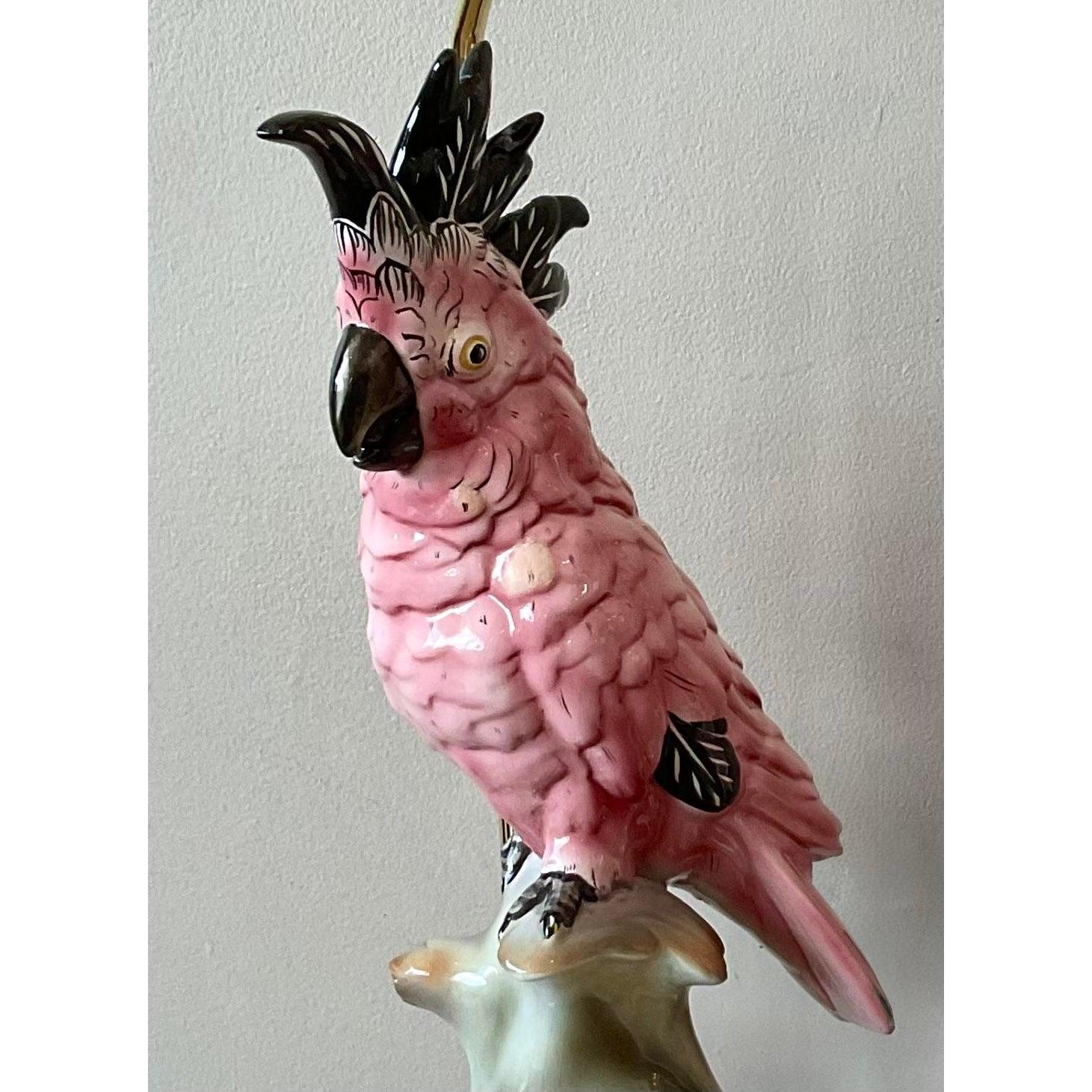This spectacular pair of vintage table lamps exudes the glamorous and exotic flair of the Hollywood Regency style. Each lamp features a beautifully sculpted and hand-painted ceramic cockatoo with a striking pink glaze, perched gracefully on a