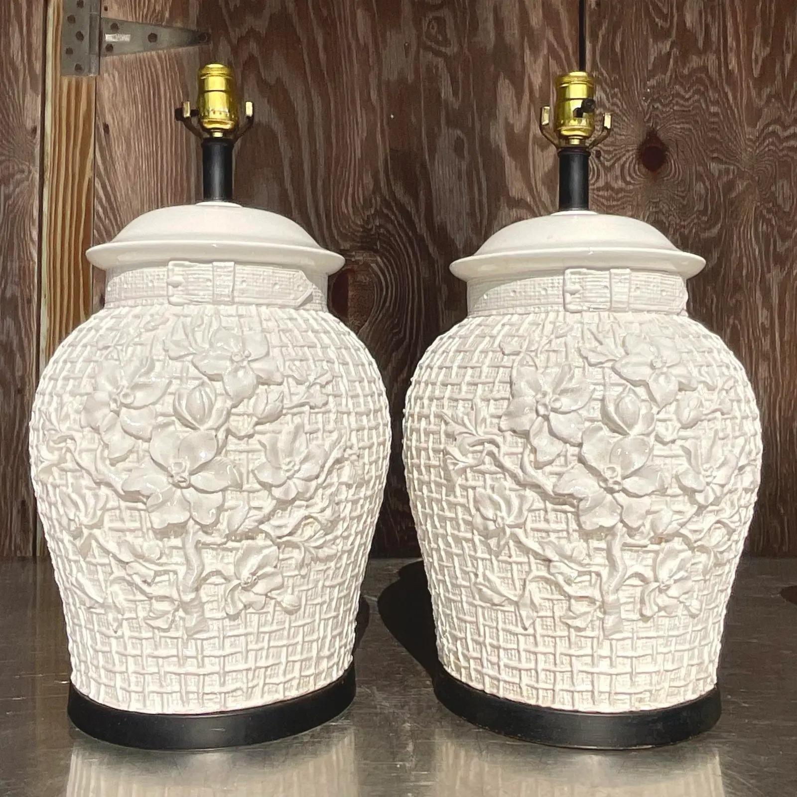 A fabulous pair of vintage Regency table lamps. Beautiful glazed ceramic lamps in a chic Icing floral design. Rest on a black plinth. Acquired from a Palm Beach estate.