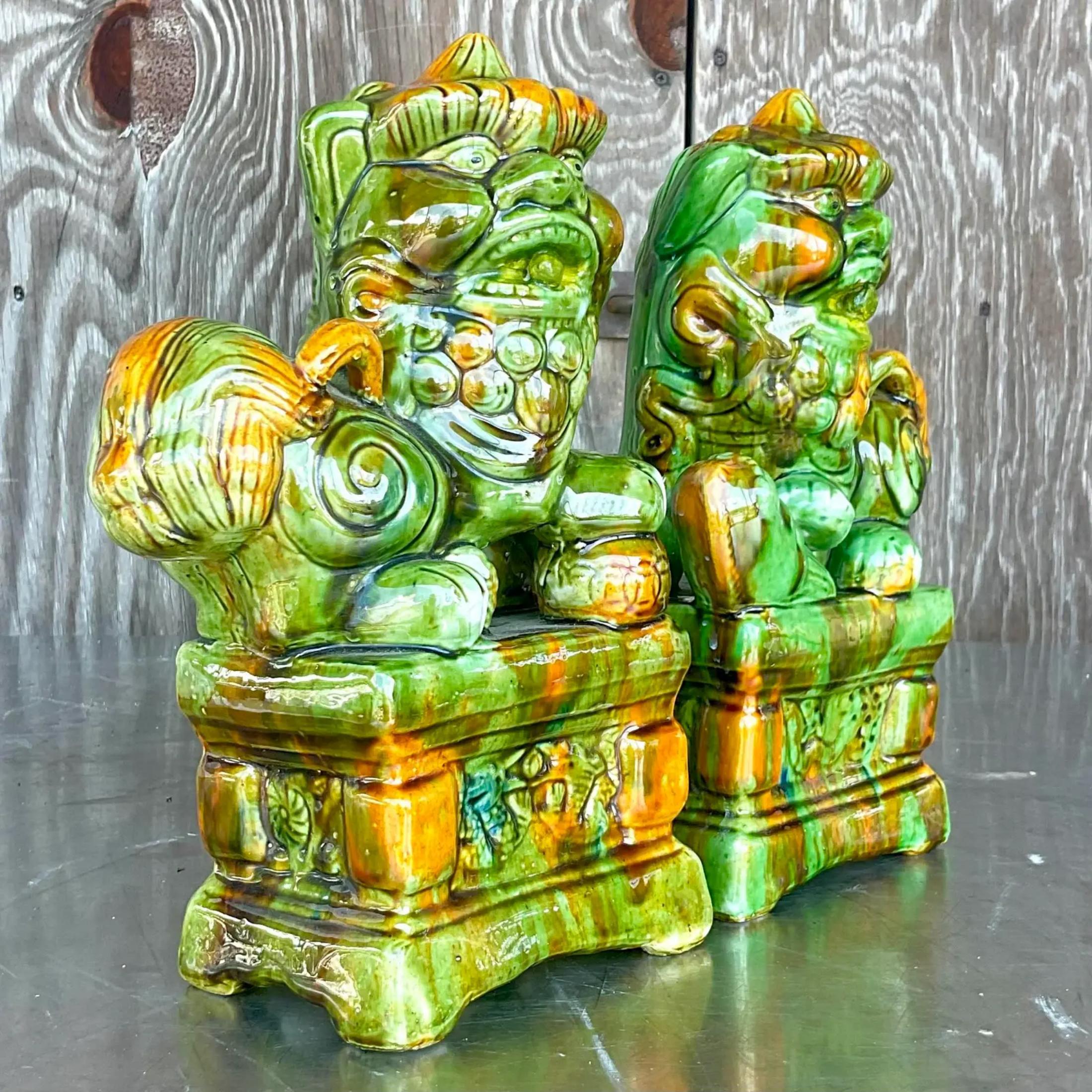 A fabulous pair of vintage Regency Foo dogs. A chic glazed ceramic in a brilliant Emerald green. Acquired from a Palm Beach estate.