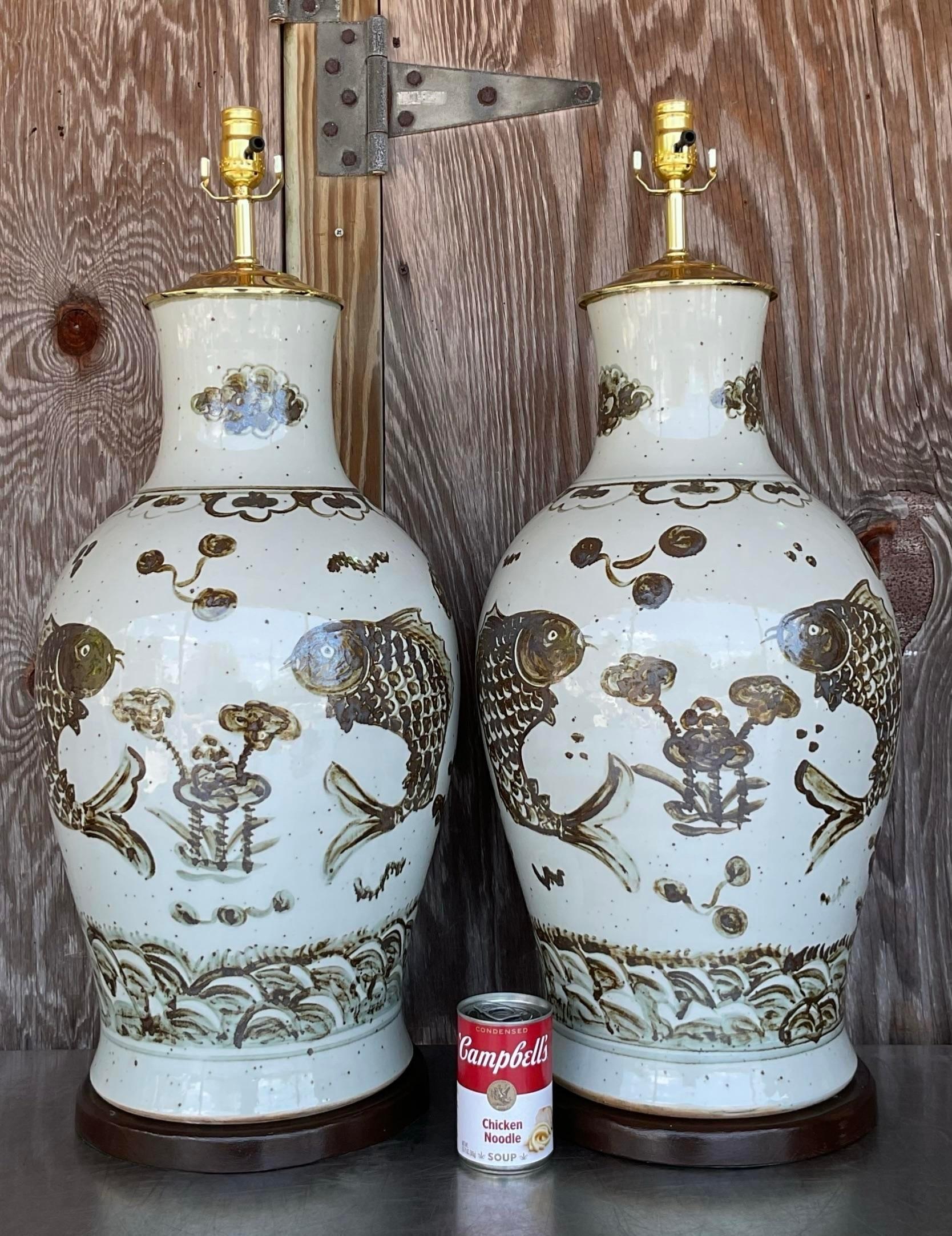 Make a splash with this pair of vintage Regency monumental glazed ceramic koi fish lamps. American-crafted with exquisite detail, these lamps capture the beauty of aquatic life, adding a touch of artistic flair and sophistication to your home