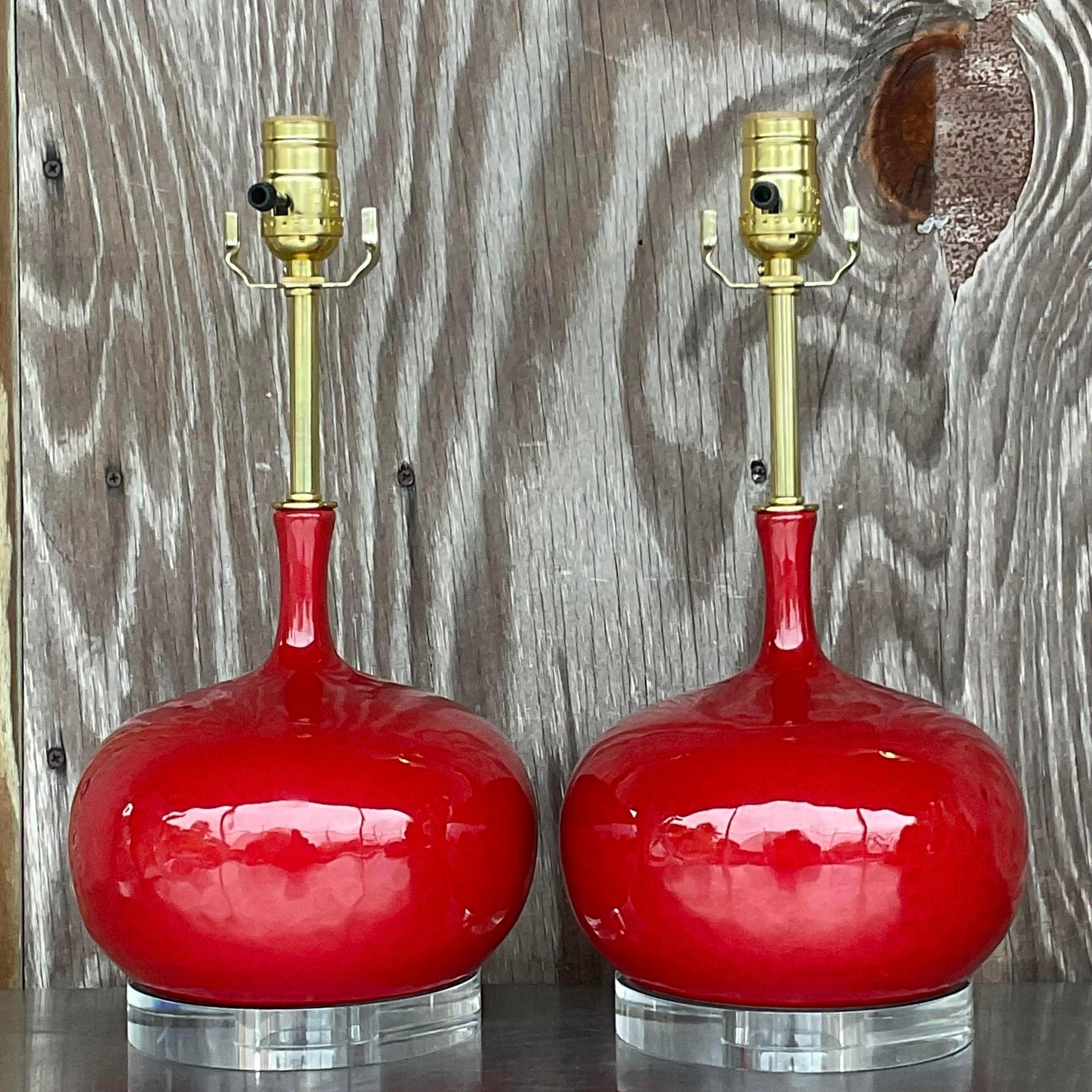 A fabulous pair of vintage Regency table lamps. A brilliant candy apple red in a glazed ceramic finish. Fully restored with all new wiring, hardware and lucite plinths. Acquired from a Palm Beach estate.