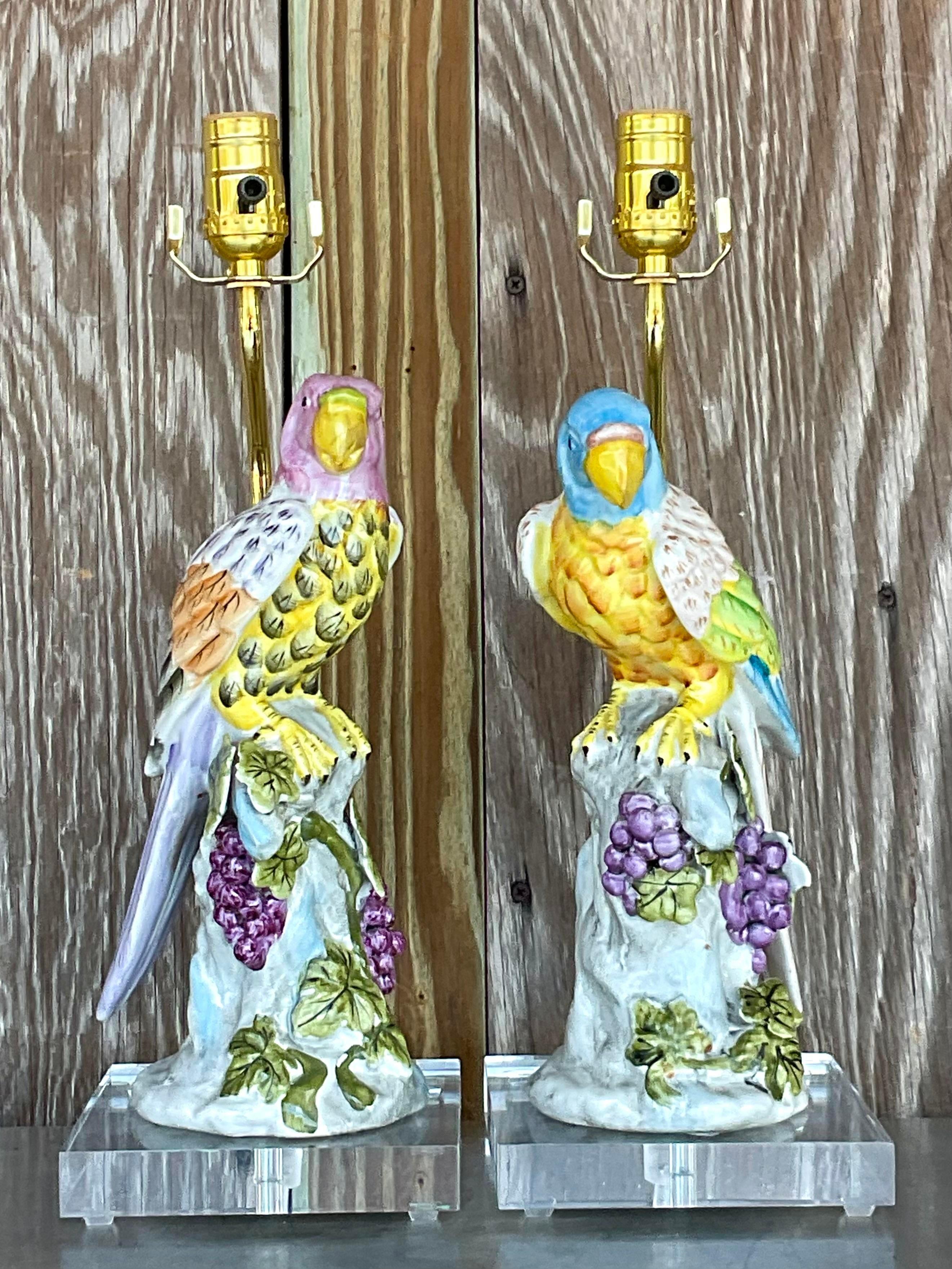Elevate your décor with a touch of exotic flair and American elegance. These vintage Regency glazed ceramic parrot lamps, sold as a pair, add a vibrant pop of color and character to any space, blending classic charm with a hint of tropical allure.