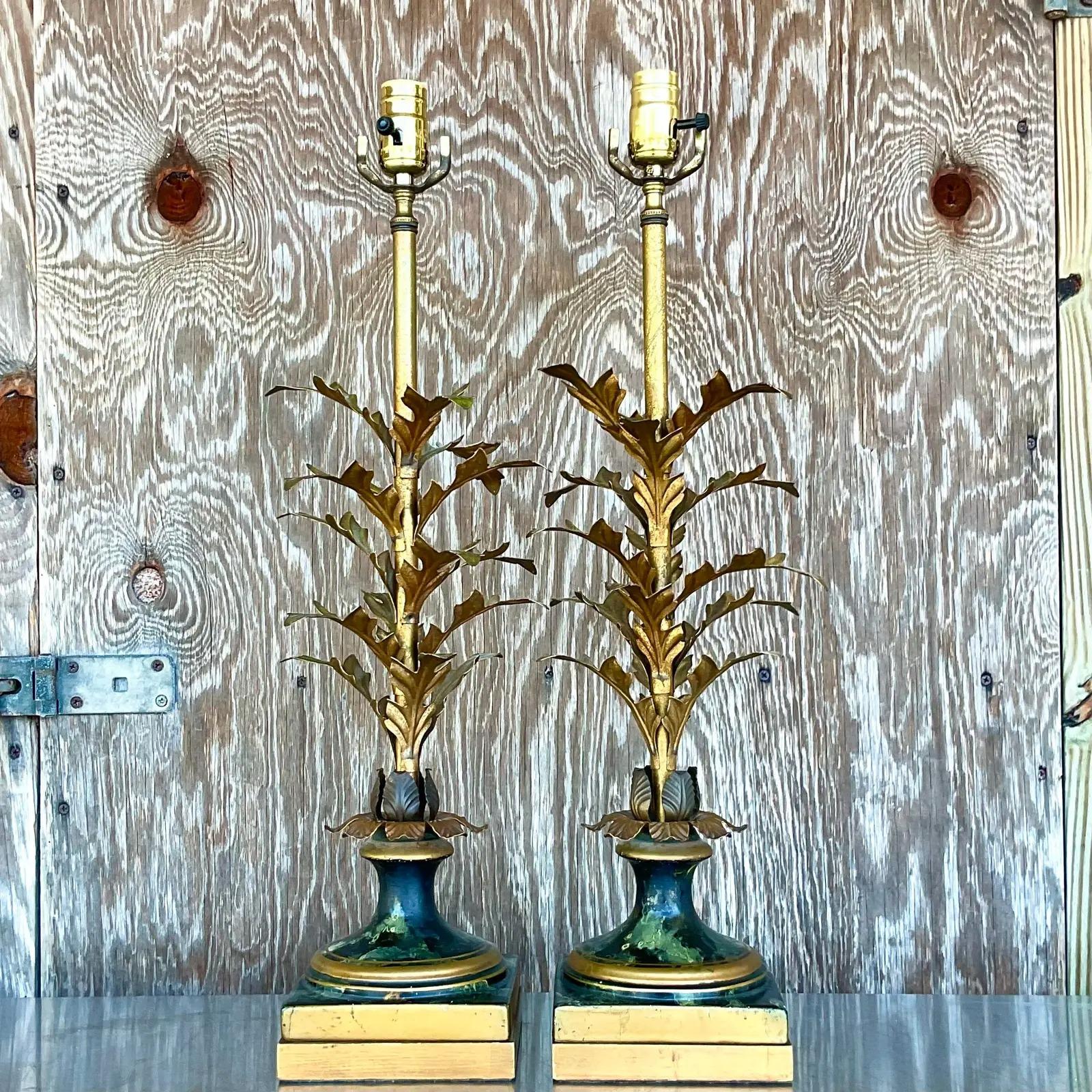 A fantastic pair of vintage Regency lamps. Beautiful leaf design with bright gilt finish. Rests on stunning hand painted plinths. Fully restored with all new wiring and hardware. Acquired from a Palm Beach estate.

The lamps are in great vintage