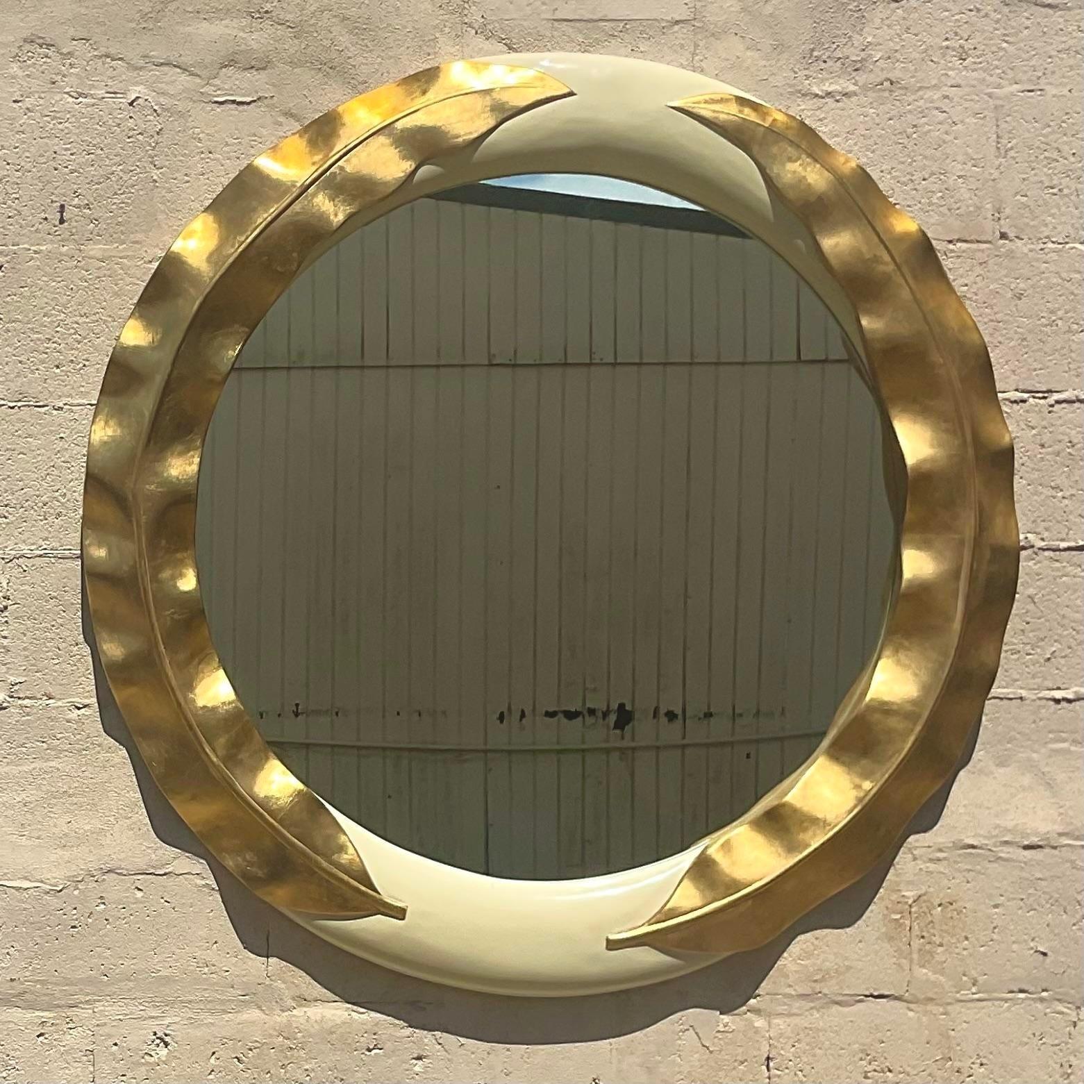 A stunning vintage Regency wall mirror. Monumental in size and drama. A chic gold leaf design on an ivory lacquered frame. Acquired from a Palm Beach estate.