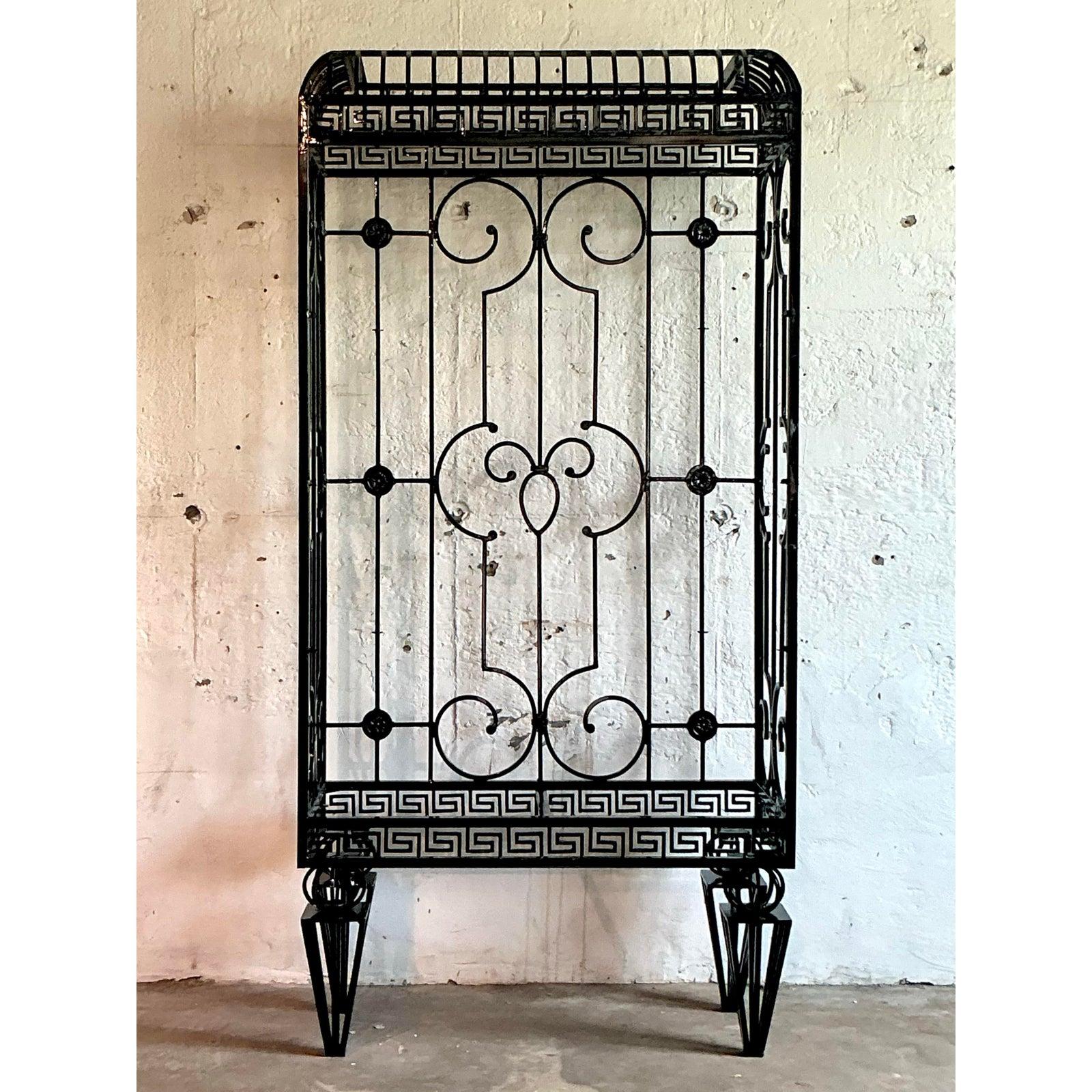 Embrace dramatic, Neoclassical elegance with this monumental vintage wrought iron etagere. Masterfully crafted, its impressive form is defined by a continuous band of iconic Greek Key fretwork, elegant scrollwork, and a stately arched top, creating