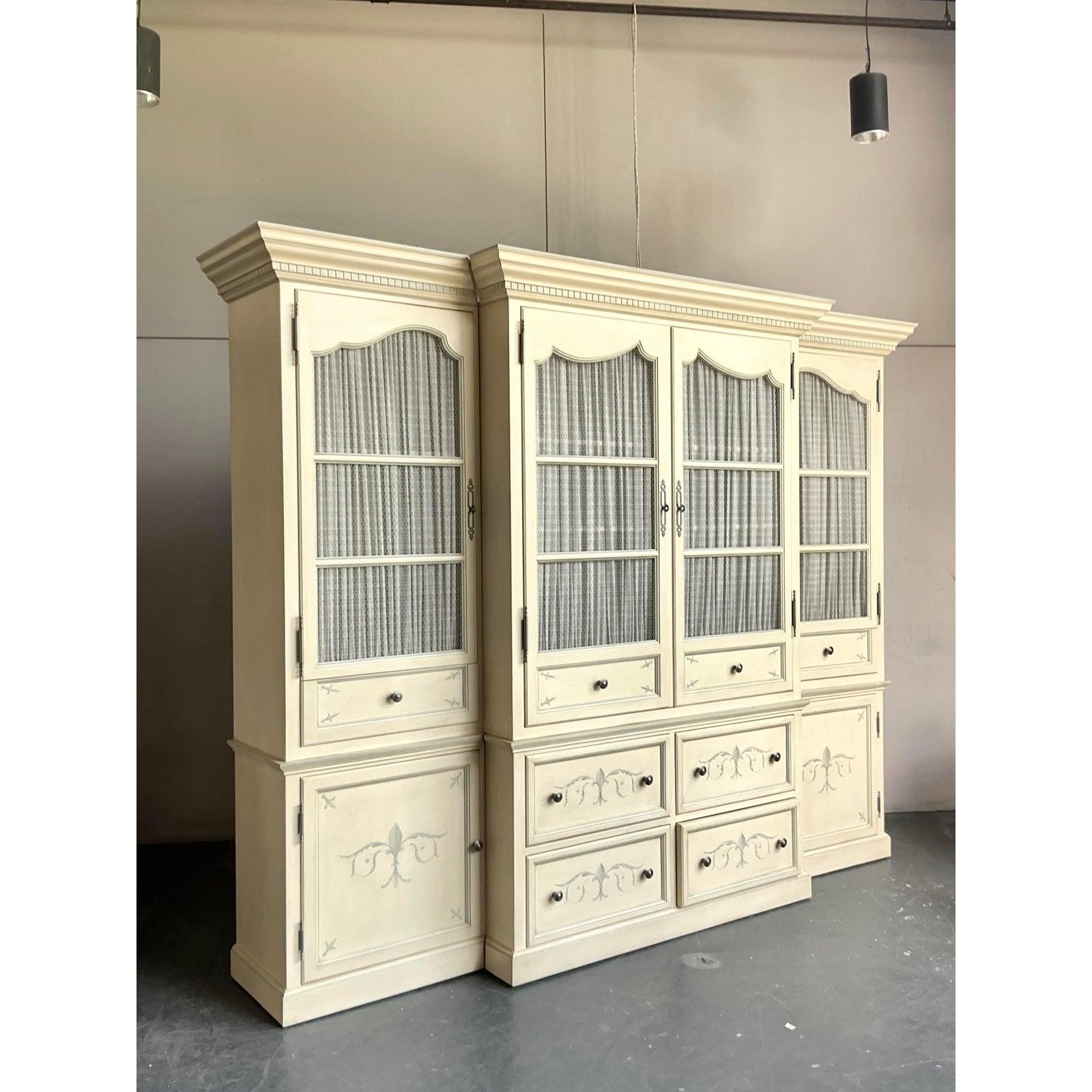 Create an immediate sense of grandeur and architectural significance with this monumental vintage breakfront cabinet. Designed in the elegant French Provincial style, this three-part wall unit is masterfully crafted and features a soft, creamy