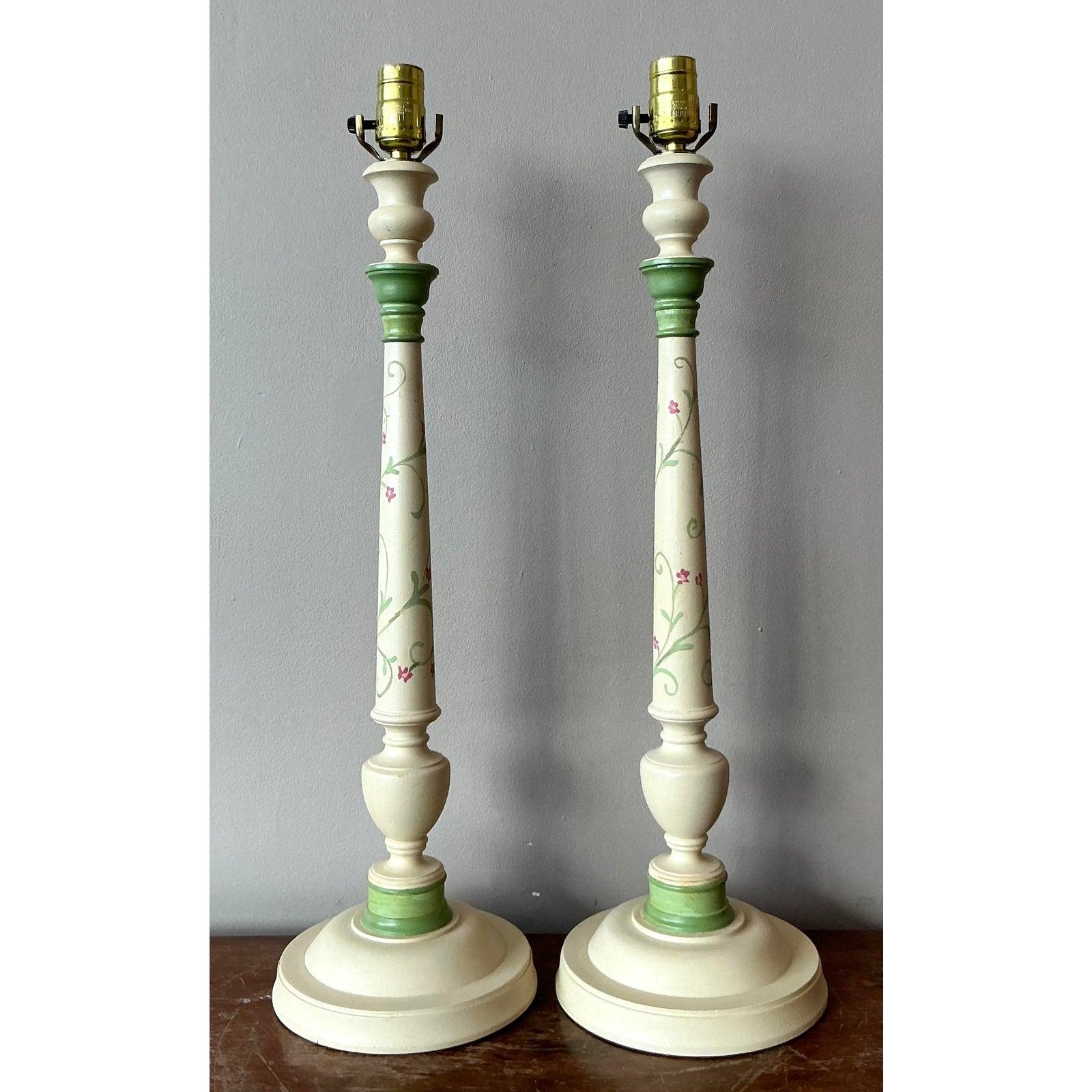 Illuminate your living space with this charming pair of vintage Regency candlestick lamps, exuding an air of classic elegance and whimsical artistry. Each lamp features a beautifully hand-painted motif of delicate pink florals and soft green