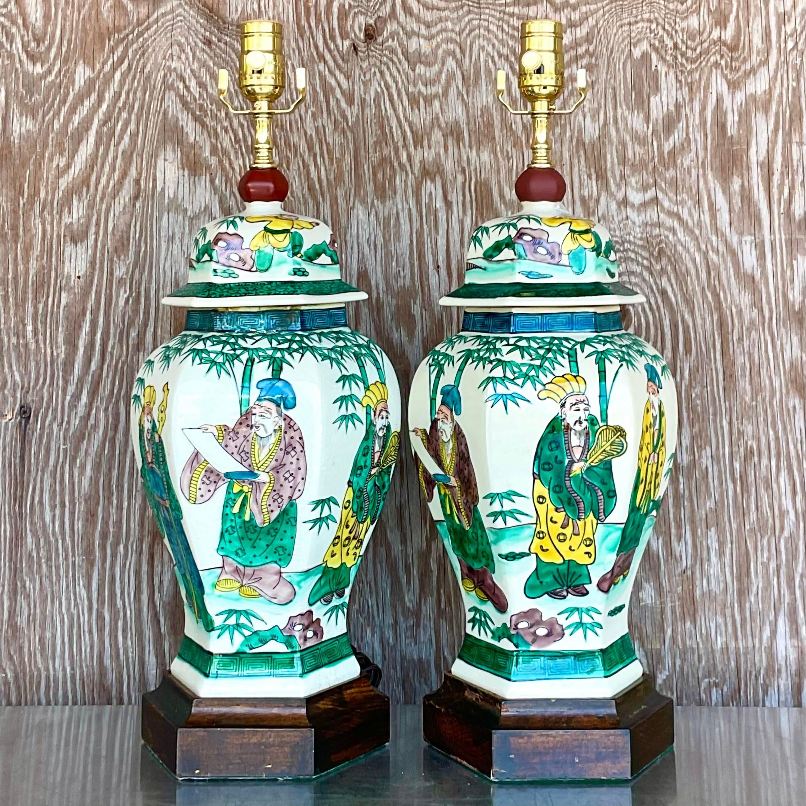 A stunning pair of vintage Asian table lamps. A beautiful hand painted Chinoiserie scene in bright clear colors. Fully restored with all new wiring and hardware. Acquired from a Palm Beach estate. 