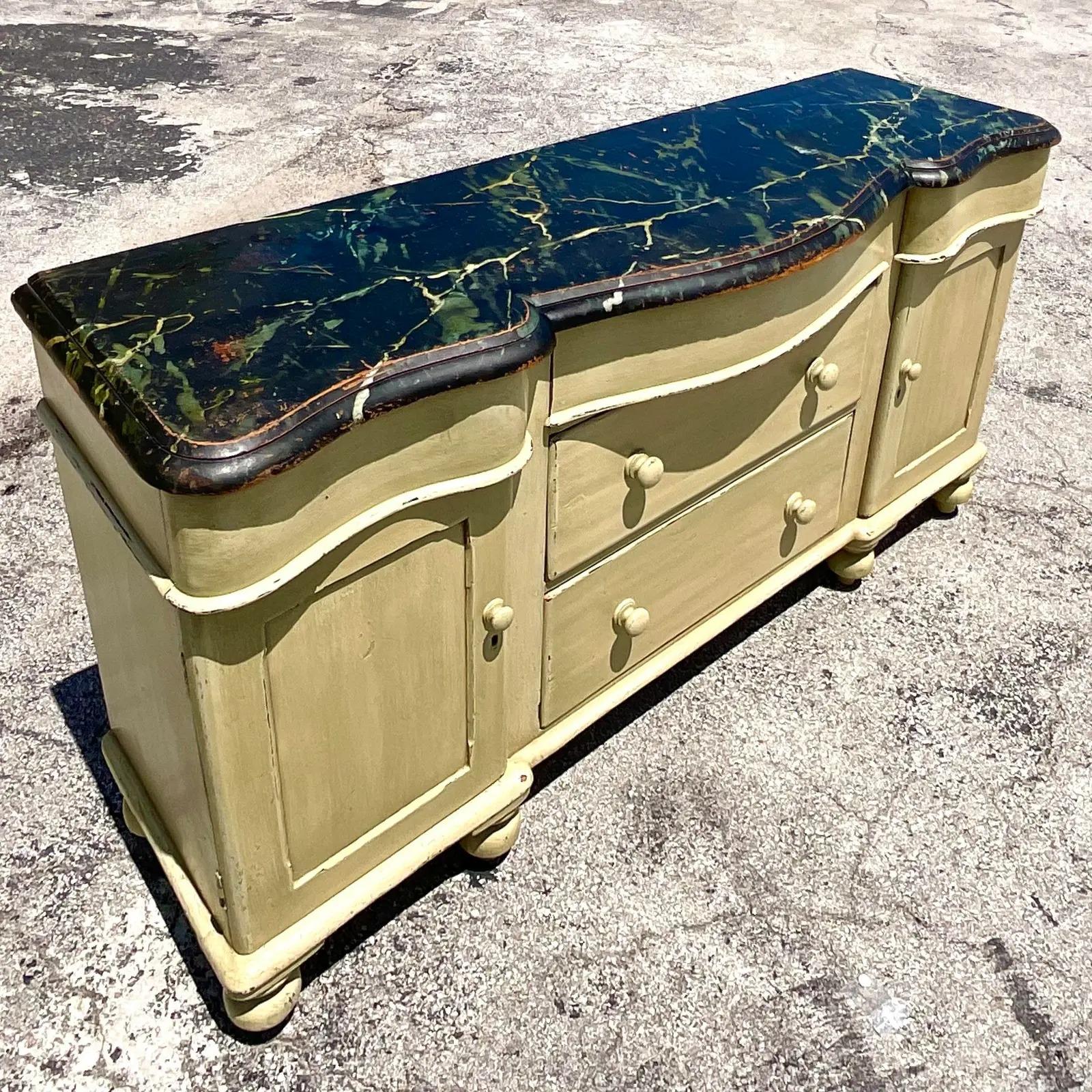 A stunning vintage Regency credenza. A chic wave front design with the most amazing hand painted faux marble top. Beautiful deep and rich colors with the natural wood peeking through. This looks like a well loved legacy piece. Just add your styling