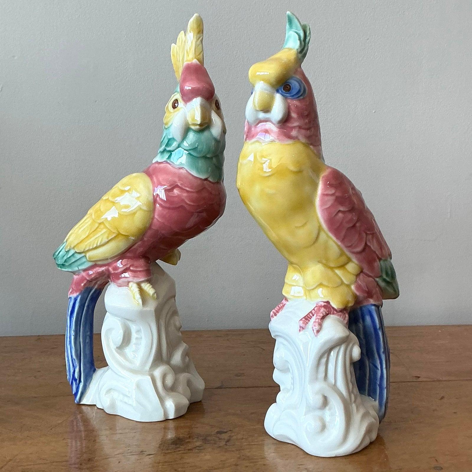 Verleihen Sie Ihrem Raum einen Hauch von skurriler Eleganz mit diesem auffälligen Set aus zwei handbemalten Keramikvögeln im Regency-Stil. Die in leuchtenden Gelb-, Rosa-, Türkis- und Kobaltblautönen gehaltenen Vögel thronen auf kunstvollen weißen