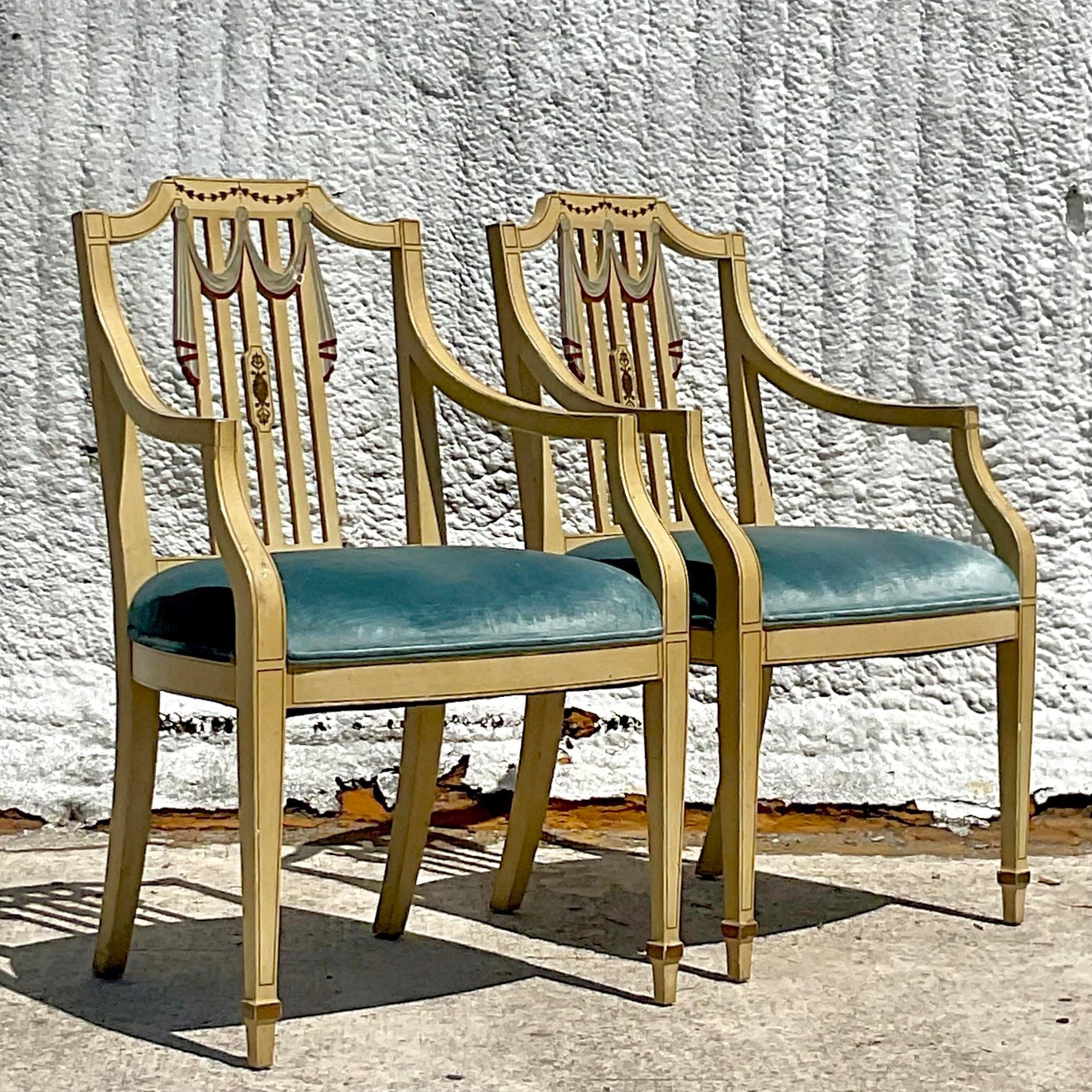 A fabulous pair of vintage Regency arm chairs. Brilliant hand painted Tromp l,oiel swag detail. Blue velvet seats with thr chic patina from time. Purchased in Italy and brought to the states. Acquired from a Palm Beach estate.