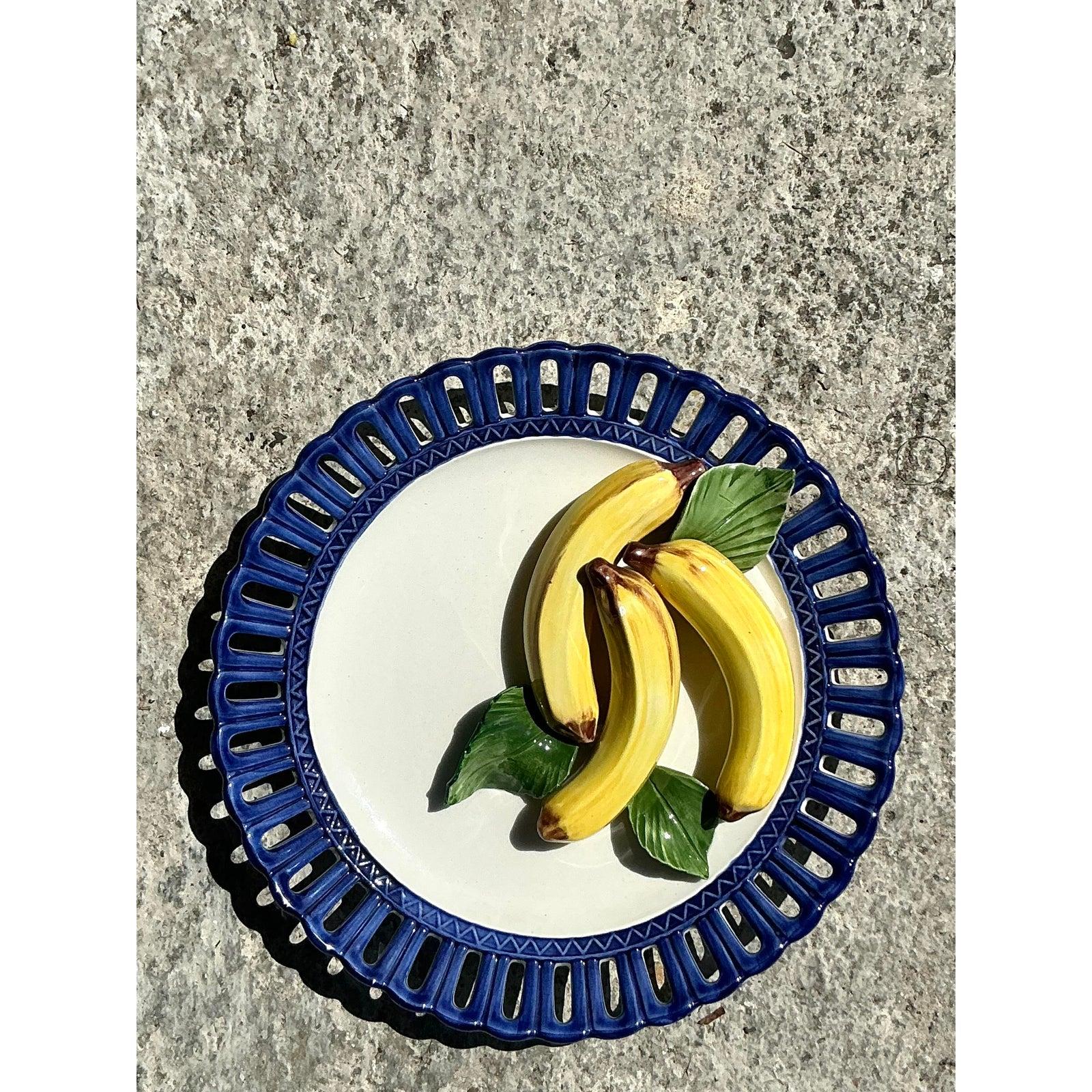 Cette superbe assiette en céramique émaillée de Horchow incarne le charme classique de la Régence avec sa bordure en treillis ajouré et ses fruits en relief peints à la main. Le cadre bleu cobalt profond contraste magnifiquement avec la céramique
