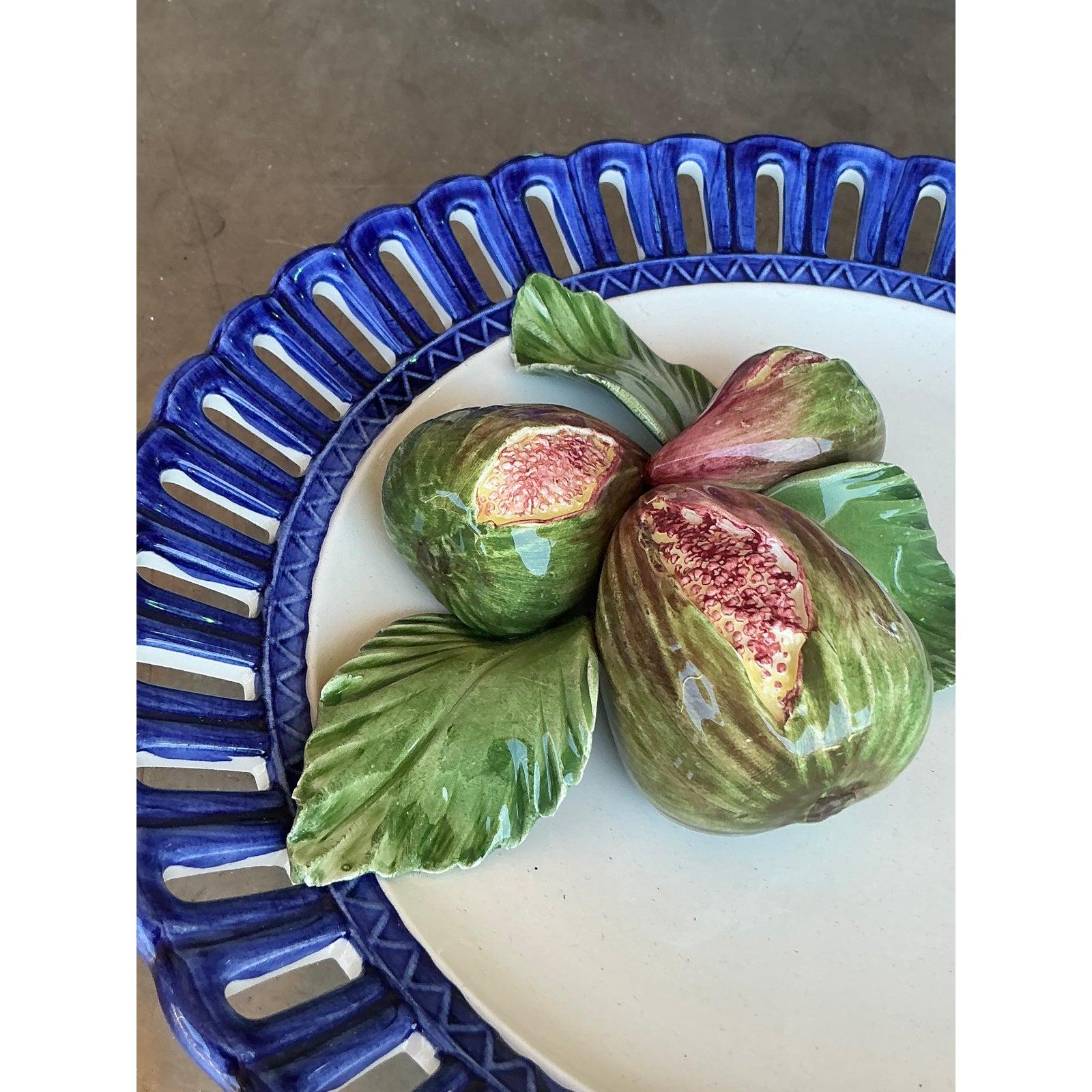 Cette exquise assiette en céramique émaillée Horchow est un mélange saisissant d'art et d'artisanat. Elle présente un arrangement sculptural de figues peintes à la main et de feuilles vertes luxuriantes. La bordure en treillis d'un bleu cobalt