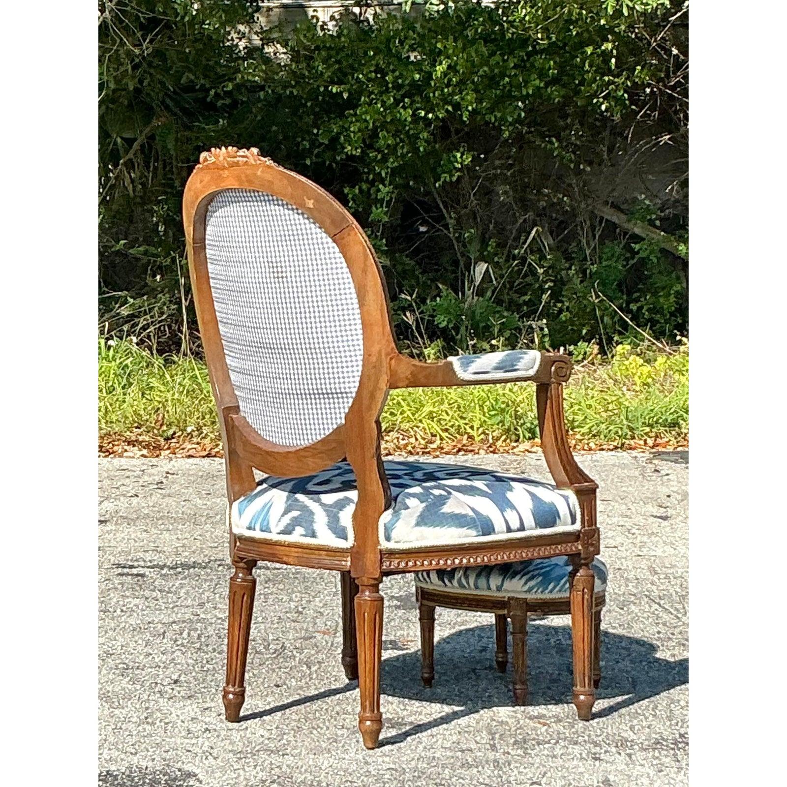 Setzen Sie einen Akzent mit diesem exquisiten Vintage-Regency-Fauteuil-Stuhl und dem dazu passenden Fußhocker, der mit einem auffälligen blau-weißen Ikat-Stoff bezogen ist. Der anmutige, handgeschnitzte Holzrahmen mit seinen filigranen Blumenmotiven