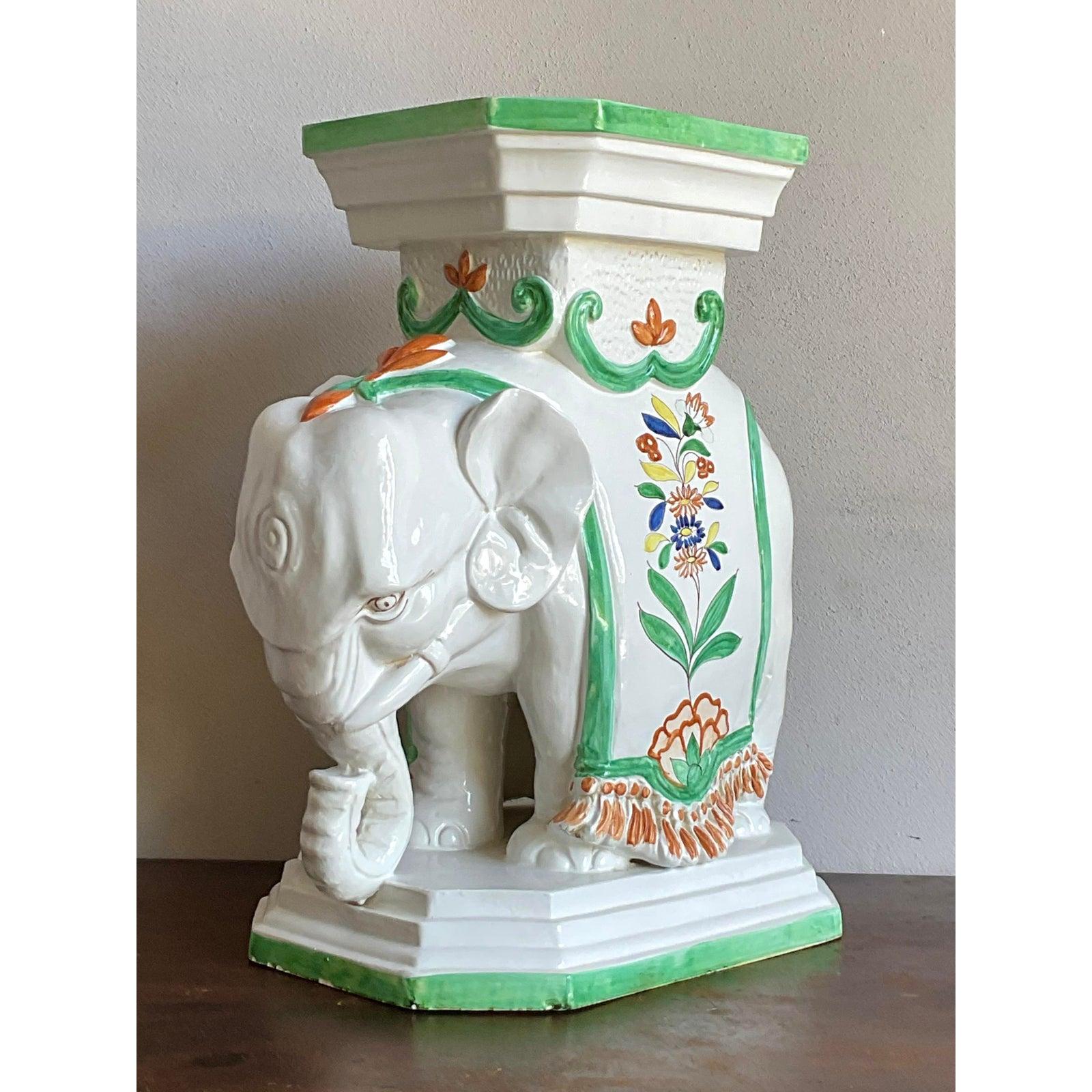Embodying exotic charm and Hollywood Regency exuberance, this vintage ceramic elephant garden stool offers a whimsical yet elegant accent piece. Crafted from glossy white glazed ceramic, the elephant is depicted in a traditional kneeling position,