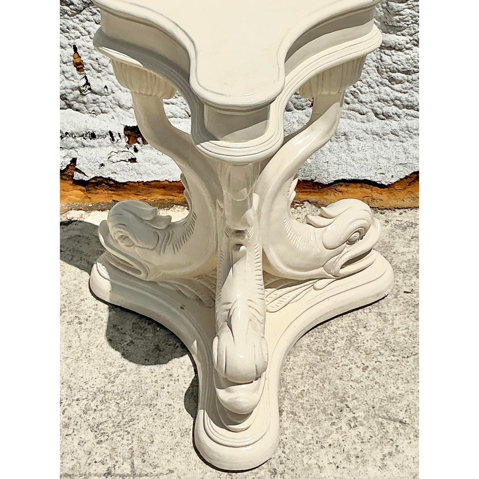 Infondi nel tuo spazio un'eleganza costiera e un fascino classico con questo sorprendente piedistallo per tavolo Delfino laccato Vintage Regency. Realizzato con una forma scultorea a tre gambe, questo piedistallo presenta figure di delfini