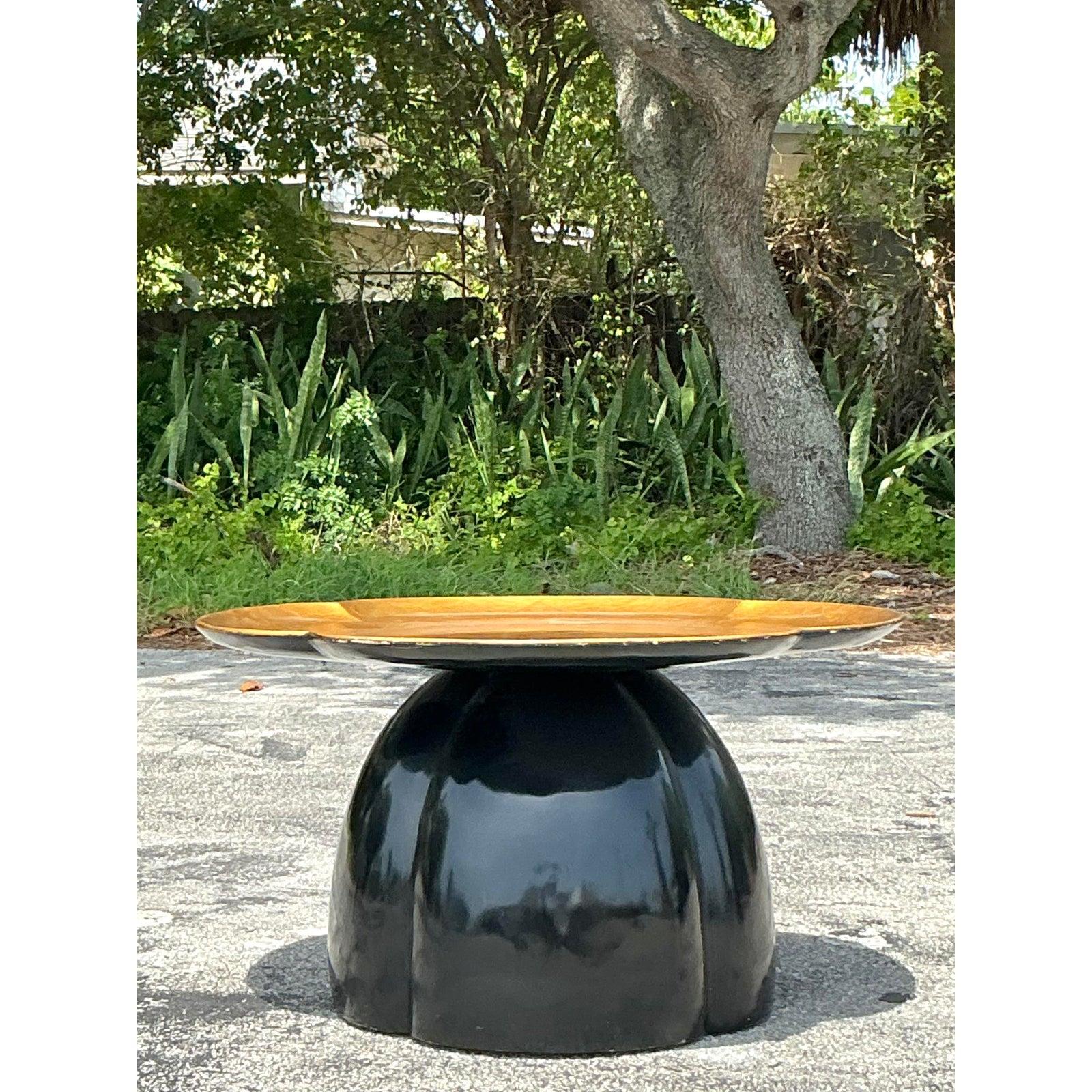 Make a luxurious statement with this exquisite vintage Regency lacquered coffee table, featuring a striking lotus design that embodies timeless glamour. The table boasts a substantial base finished in sleek black lacquer, sculpted into an elegant,