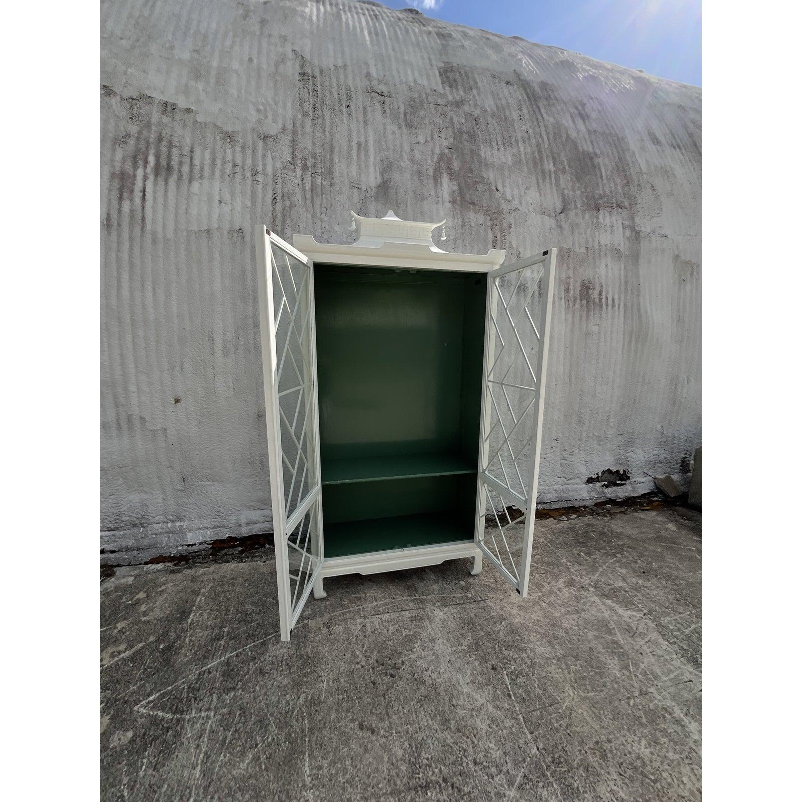 Spectacular vintage pagoda display cabinet. Gorgeous white lacquered finish with a sea foam green interior. Three interior shelves. Chic pagoda roofline with a Greek Key border and tipped with charming little bells. Acquired from a Palm Beach estate.