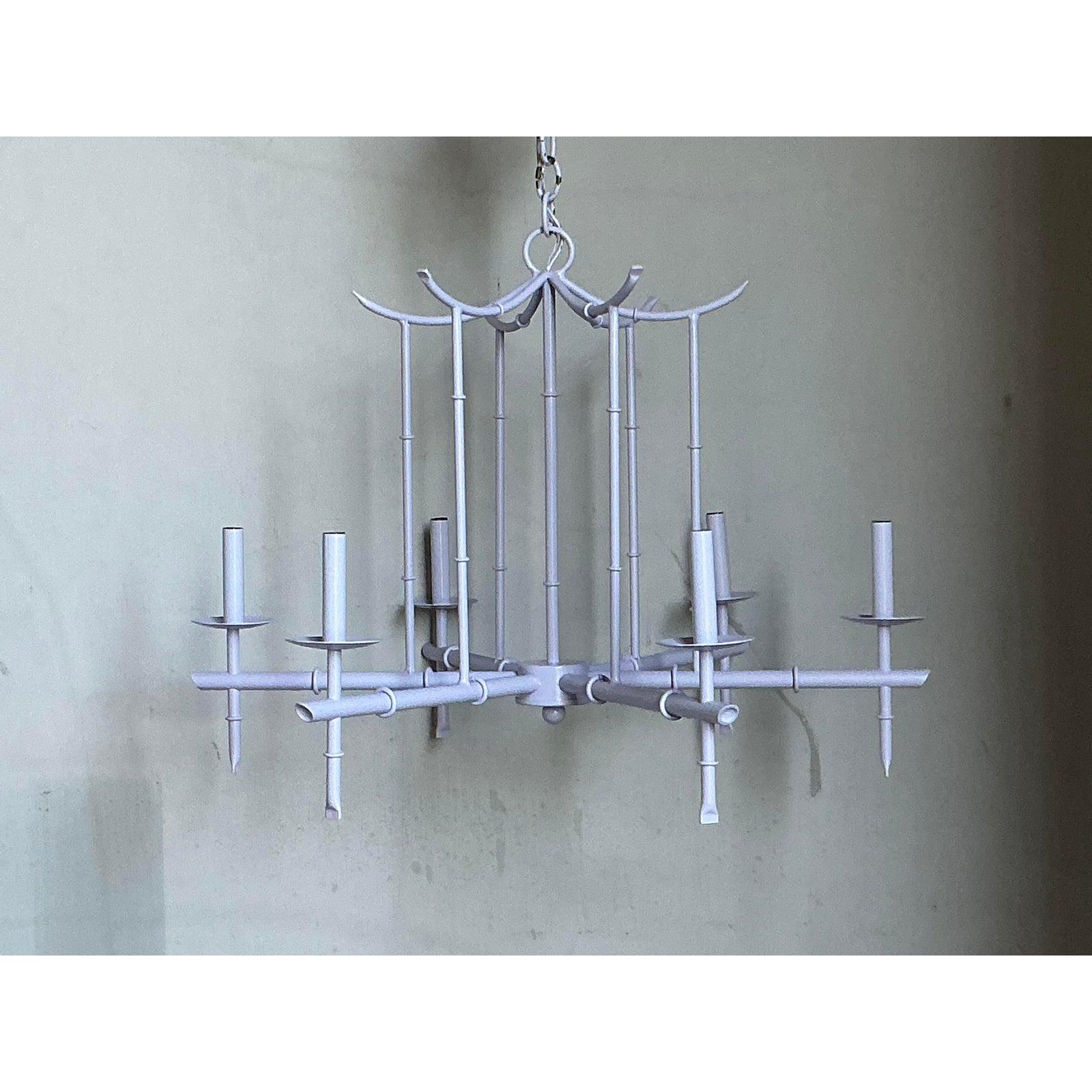 Questo iconico lampadario d'epoca è uno splendido esempio degli stili Chinoiserie e Hollywood Regency che hanno dominato il glamour della metà del secolo. La struttura imita i pali di bambù, meticolosamente realizzata in metallo leggero e rifinita