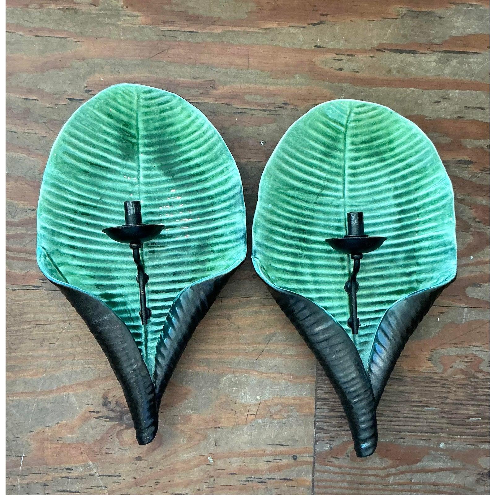Voici une paire captivante d'appliques murales vintage à feuilles en céramique, magistralement fabriquées dans le style estimé Hollywood Regency et rappelant l'esthétique convoitée de Covet House. Chaque applique présente une forme de feuille