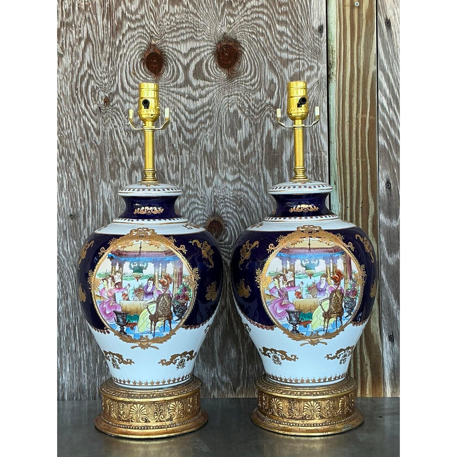 Este exquisito par de lámparas vintage de porcelana estilo Limoges desprende opulencia con su fondo azul cobalto intenso, sus fastuosos detalles dorados y sus escenas figuradas pintadas a mano. Las románticas representaciones neoclásicas muestran