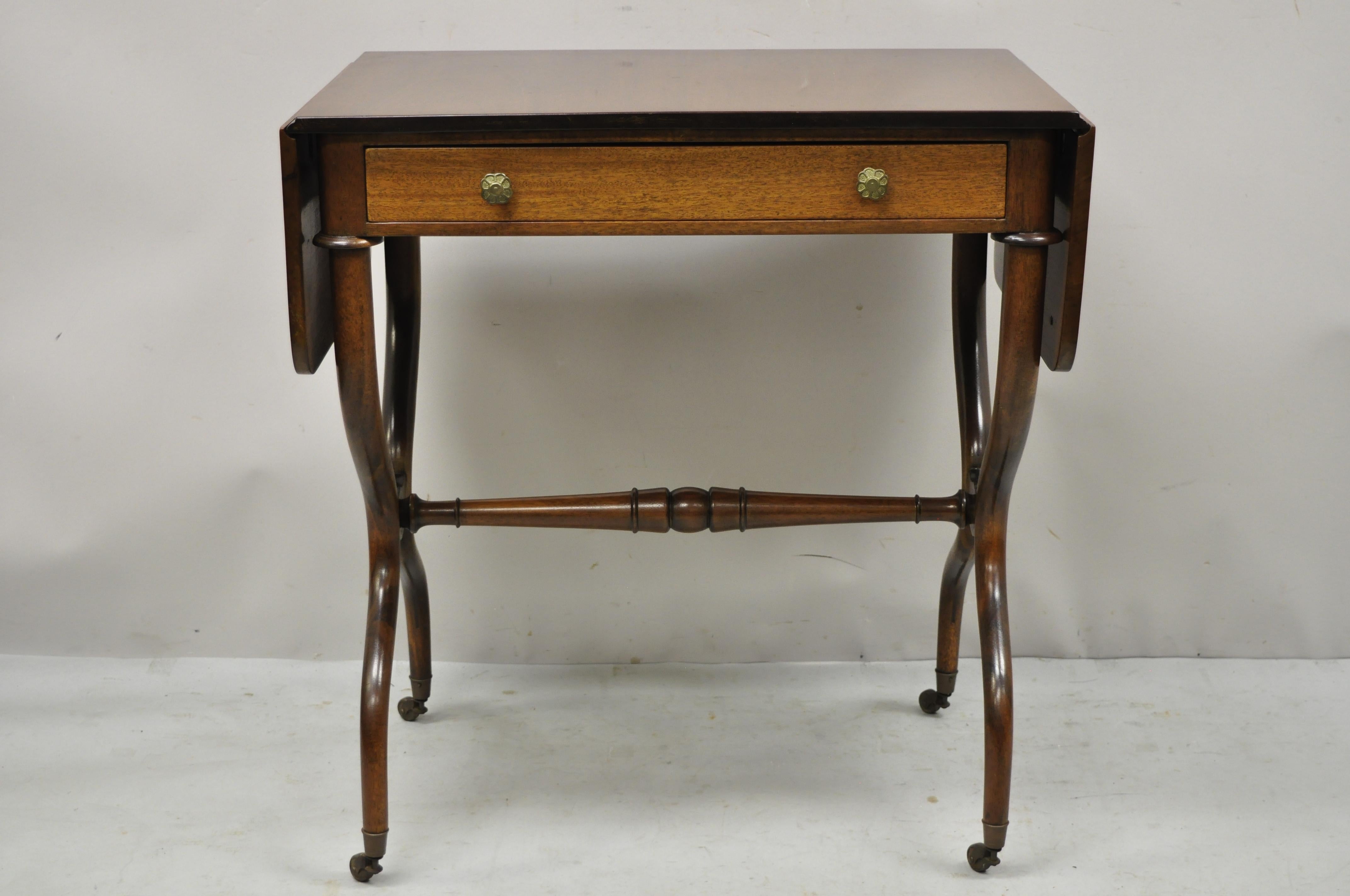 Vintage English Regency mahogany drop leaf pembroke one drawer lamp side table small desk. Item features 2 drop leaf sides, shapely stretcher base, brass rolling casters, beautiful wood grain, finished back, 1 dovetailed drawer, very nice vintage