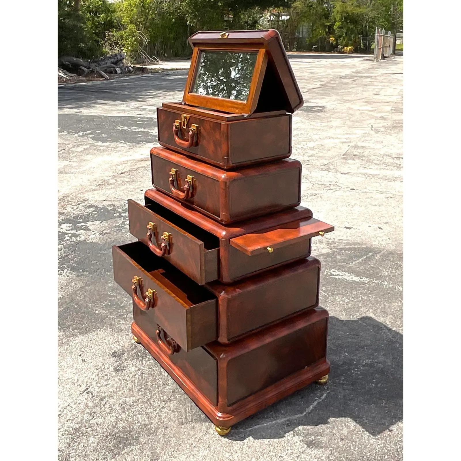 Stunning vintage Regency chest of drawers. Made by the iconic Maitland Smith group. Beautiful Flame mahogany with leather trim. Charming stacked luggage design with all kinds of drawers, pull out trays and pop up mirrors. A really magical piece.