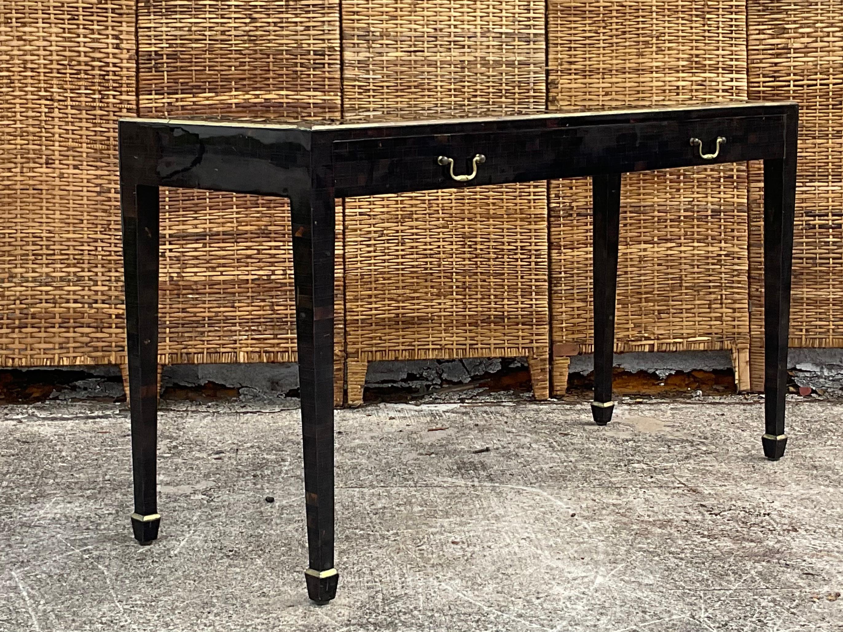 An incredible vintage Maitland Smith console table. A sleek design with a tessellated horn frame with feathered gilt detail. An inset glass top reveals the table is actually used to house a persons treasure collection. A drawer that pulls out with a