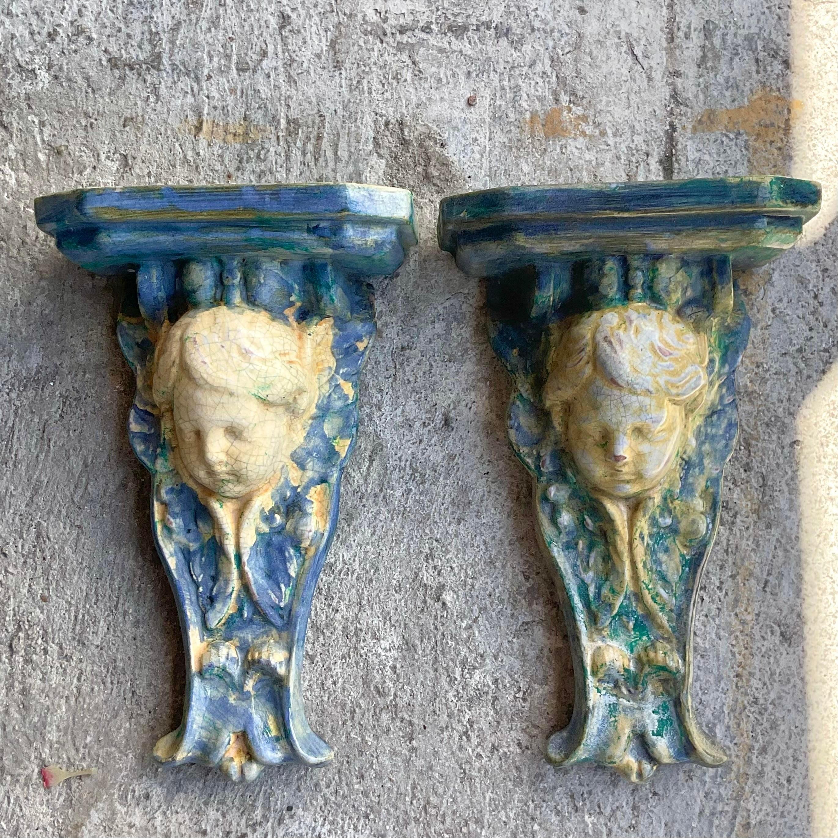 Enhance your walls with this pair of vintage Regency majolica cherub brackets. Merging classic Regency elegance with American taste, these brackets feature charming cherub motifs, adding a touch of whimsy and sophistication to any room.