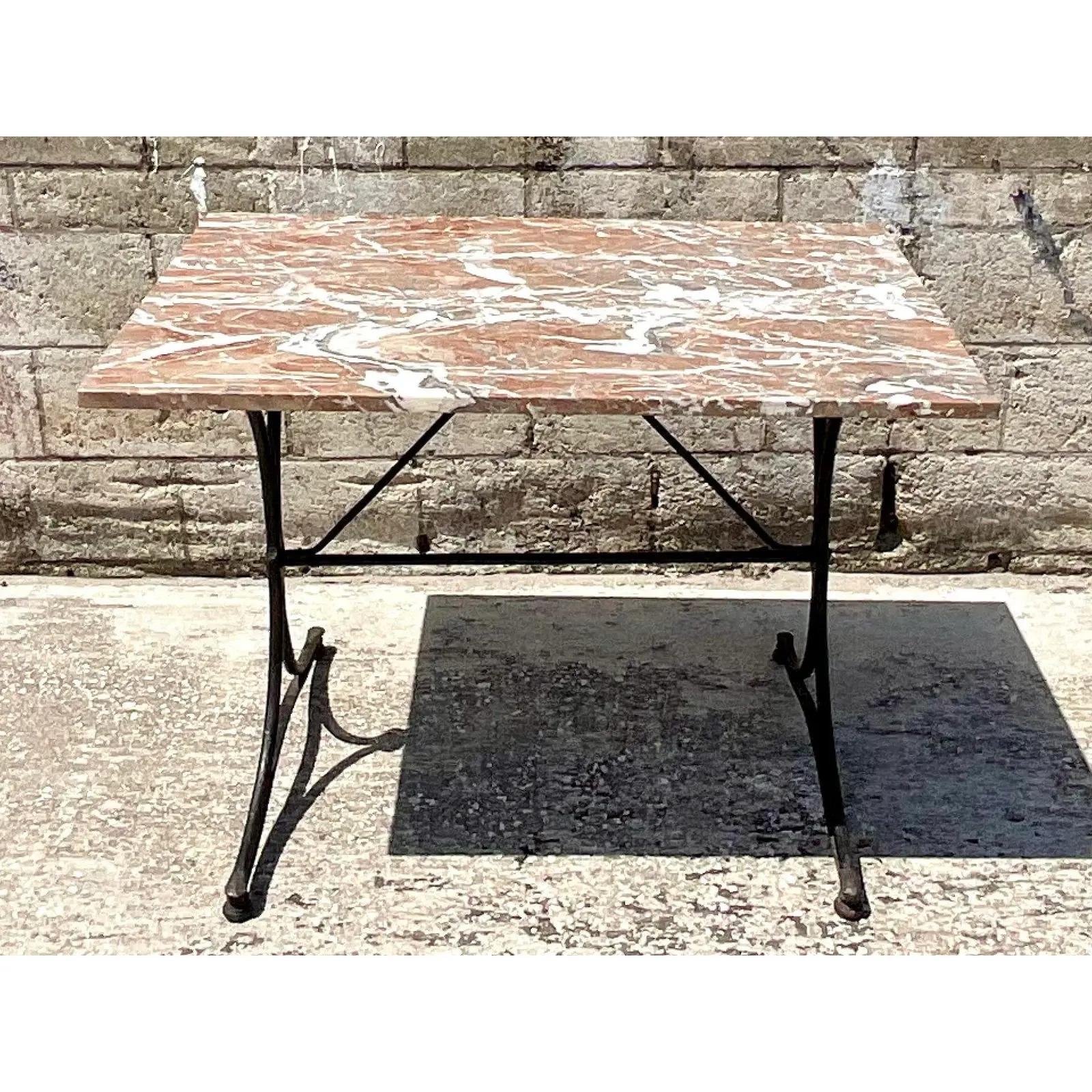 A fantastic vintage Regency dining table. Beautiful rust colored marble on a black wrought iron base. Acquired from a Palm Beach estate.