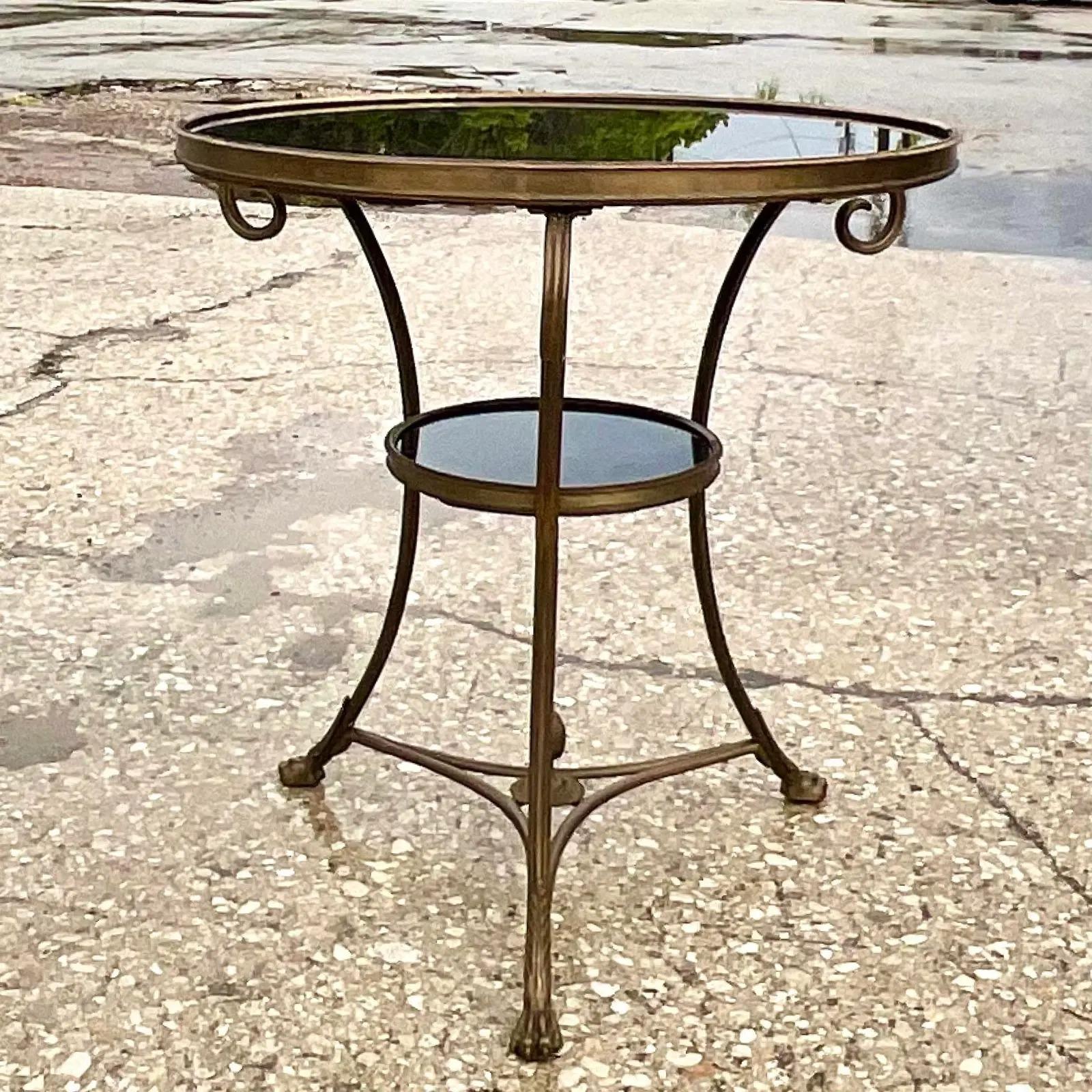 Fantastic vintage Regency side table. A beautiful black marble top in a chic Gueridon shape. Elegant brass frame with two levels. Acquired from a Palm Beach estate.
