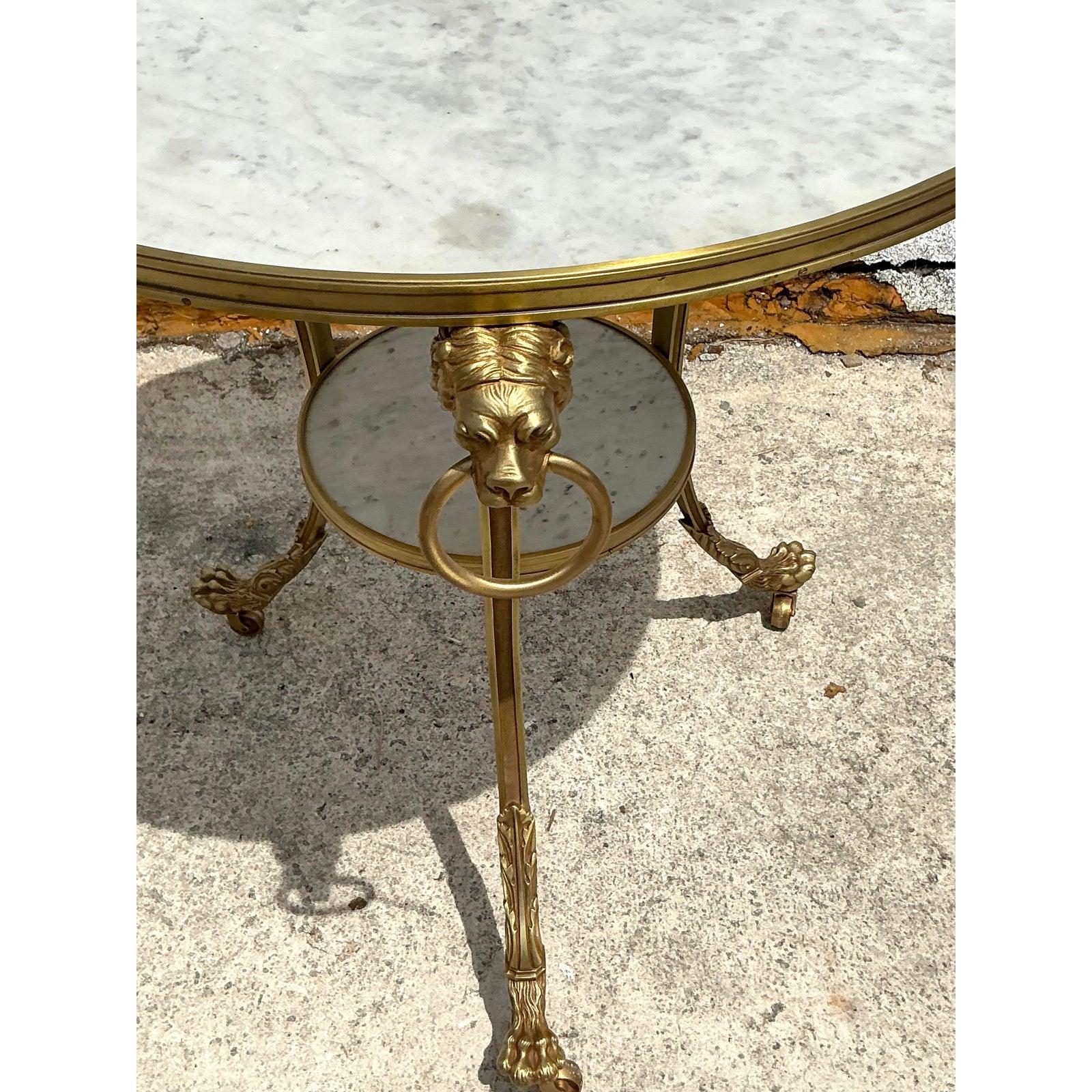 L'élégance intemporelle et le charme opulent de cette table de guéridon Vintage Regency à plateau en marbre. Dotée d'un plateau circulaire en marbre blanc et d'un plateau inférieur assorti, cette pièce exquise est soutenue par des pieds en laiton
