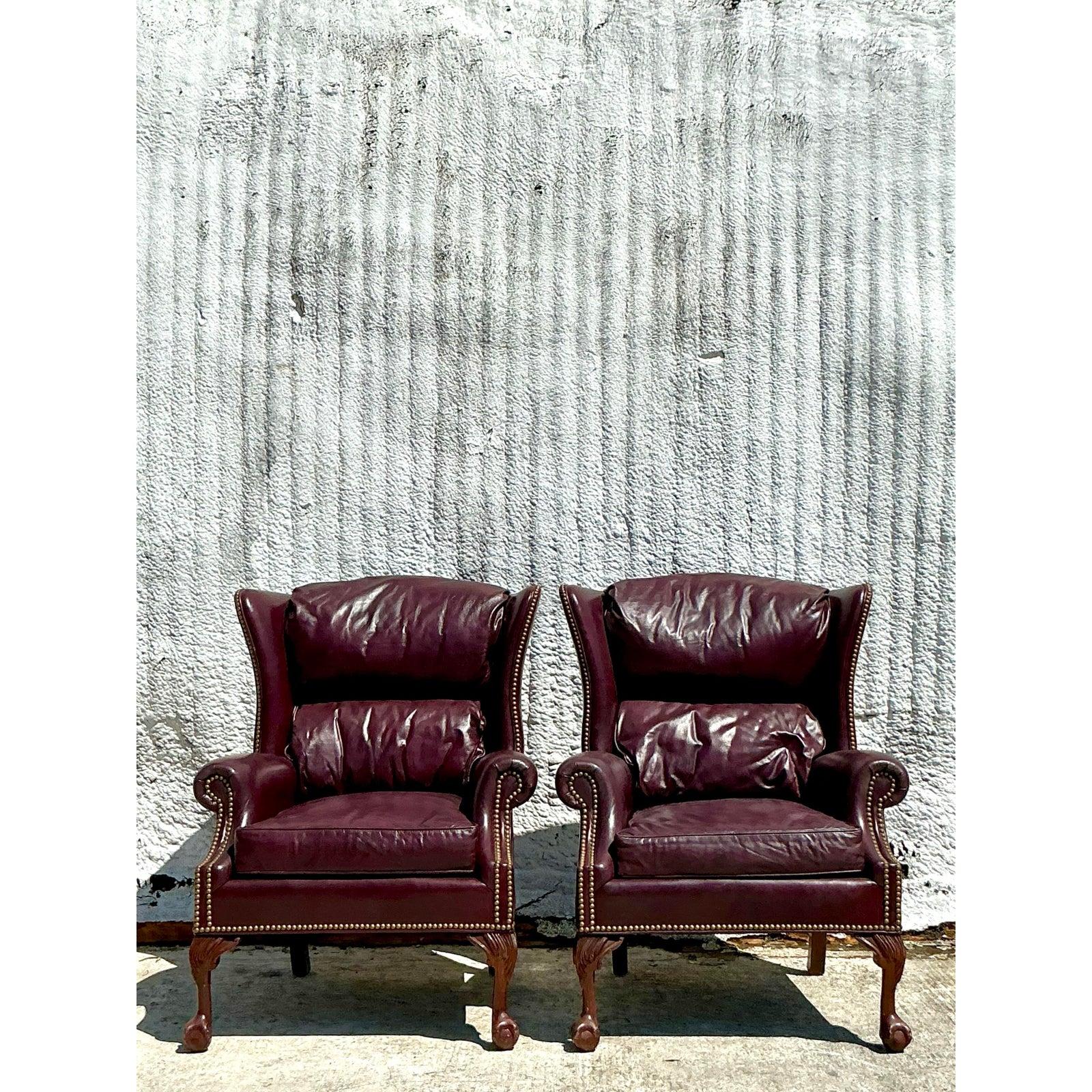 Faites une déclaration audacieuse et intemporelle avec cette paire de fauteuils à oreilles de style Vintage Regency, richement rembourrés en cuir merlot profond. La silhouette à haut dossier, les accoudoirs roulés et la garniture de tête de clou
