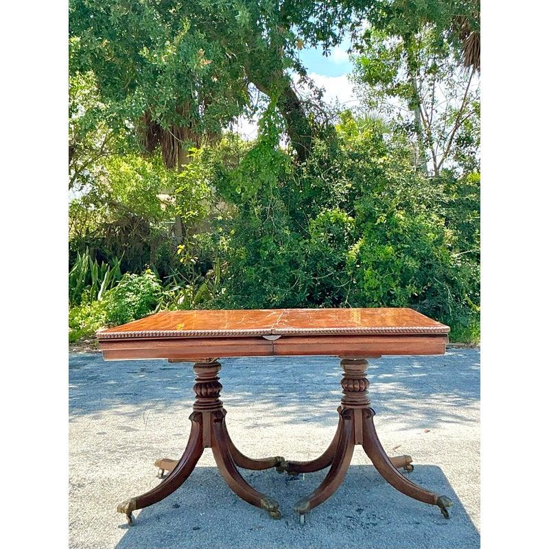 Command attention with this magnificent Vintage Regency Monumental Extendable Duncan Phyfe Table, a true heirloom piece destined to be the centerpiece of grand gatherings. This extraordinary table boasts a deep, lustrous mahogany finish, showcasing
