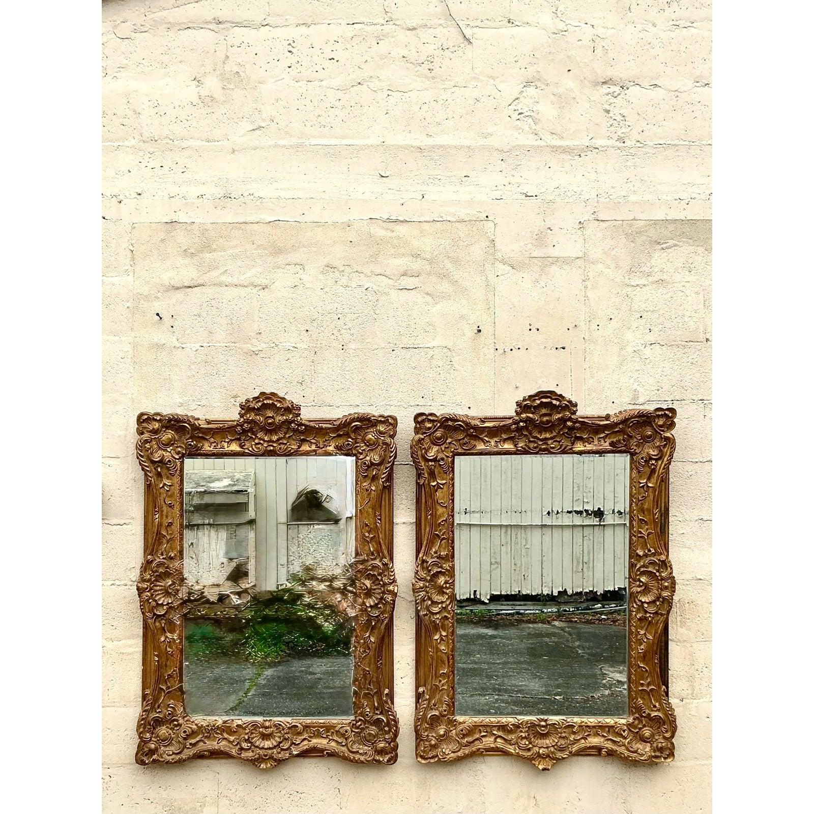 Aggiungi un tocco di eleganza senza tempo ai tuoi interni con questa splendida coppia di specchi dorati in stile Regency vintage. Ogni specchio vanta una cornice in legno intagliata con intricati motivi floreali e conchiglie, rifinita in una ricca