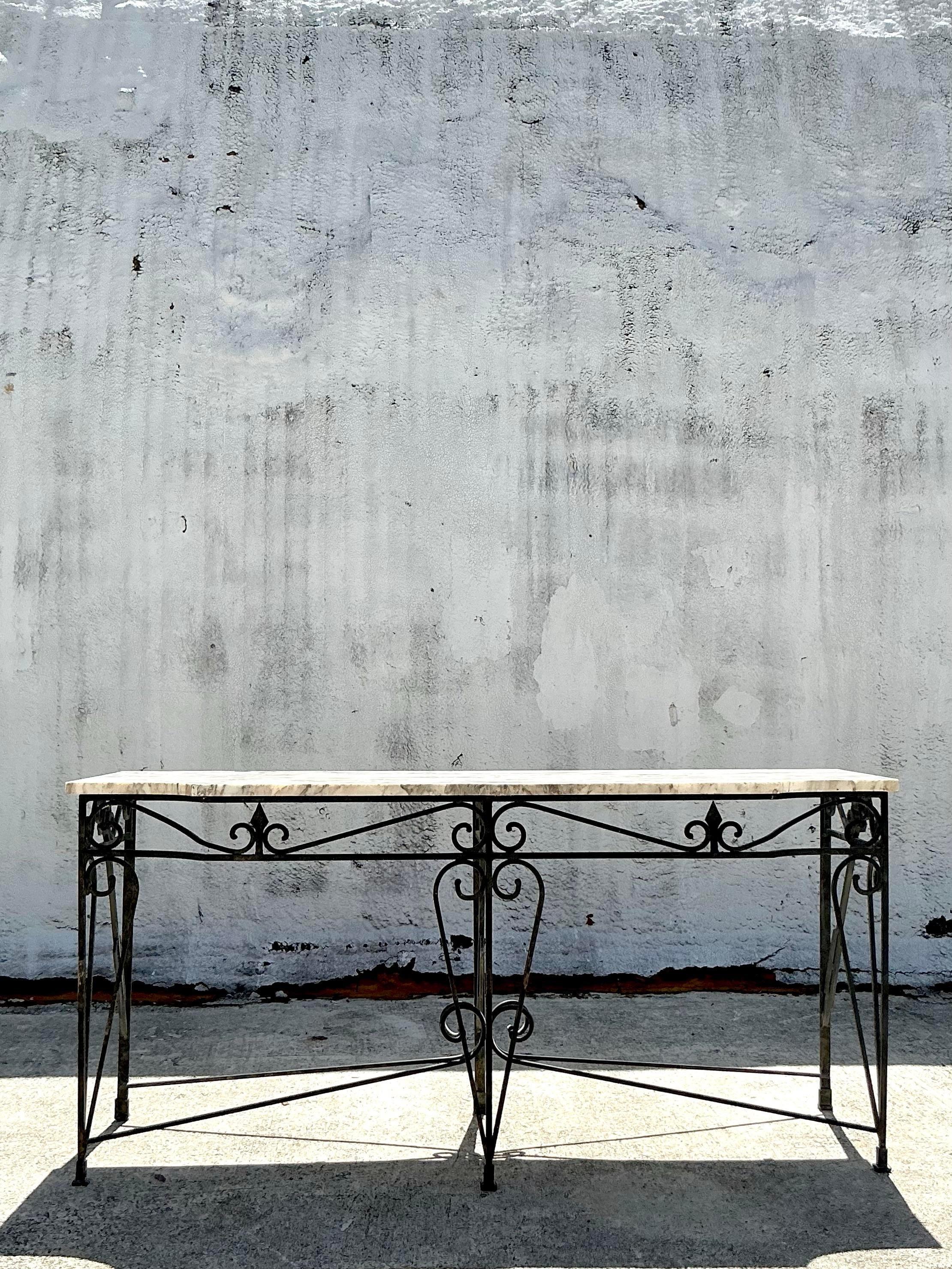 An extraordinary vintage Regency console table. A chic wrought iron frame with a stunning arrow design in the metal work. A beautiful all over patina on the stone top. Monumental in size and drama. Acquired from a Palm Beach estate.