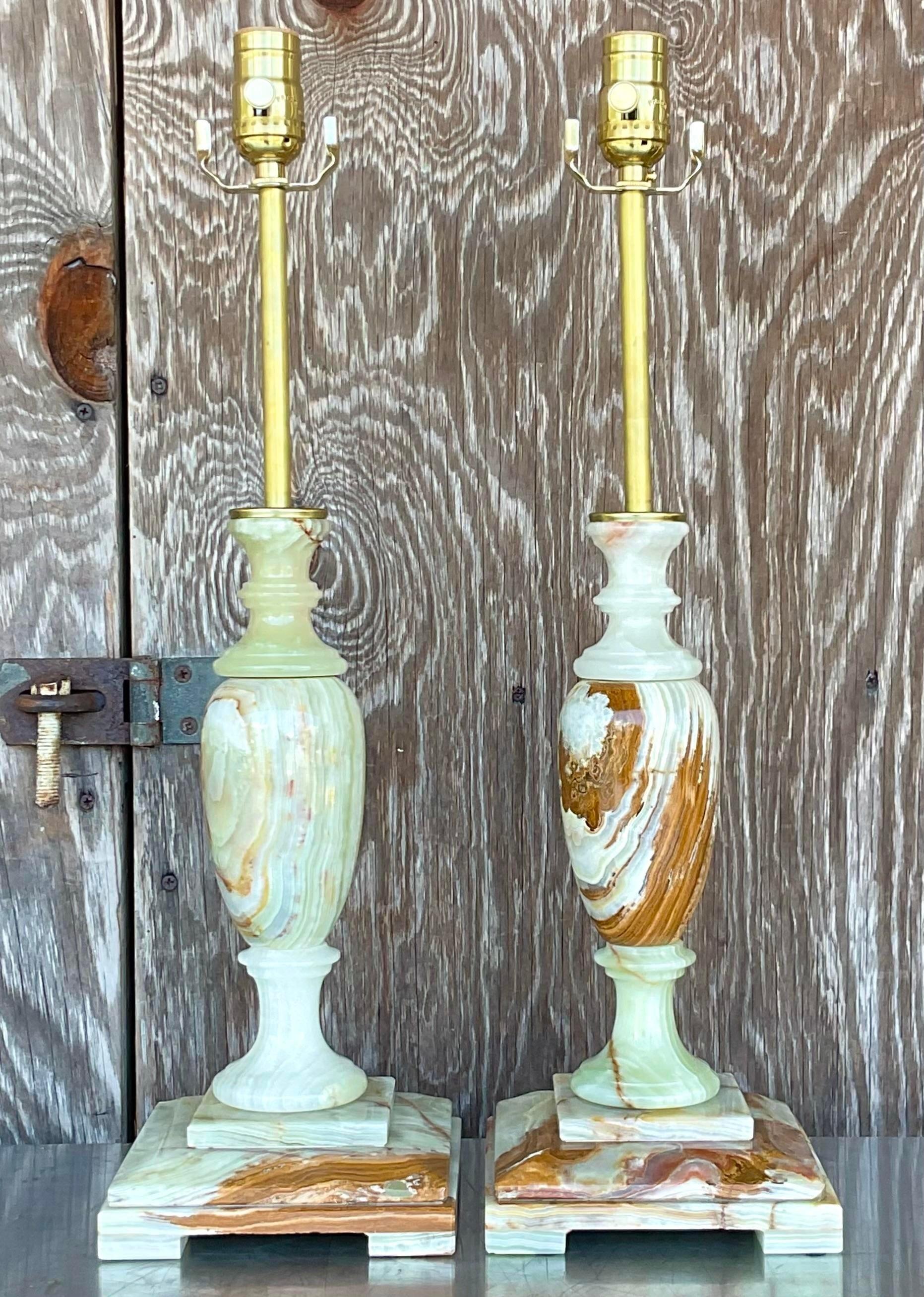 A fabulous pair of vintage Regency table lamps. Beautiful candlestick style in onyx. Incredible coloration and veining in the stone. Fully restored with all new wiring and hardware. Acquired from a Palm Beach estate.